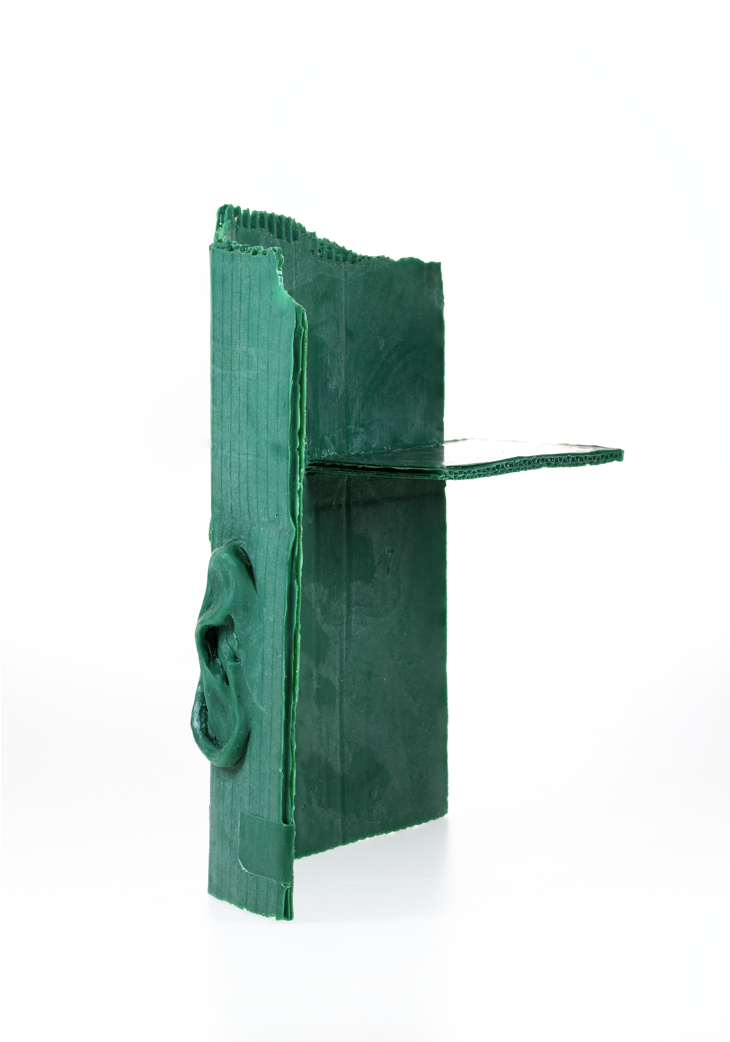 Green piece of cardboard with a 3D ear attached, standing vertically against a white background.