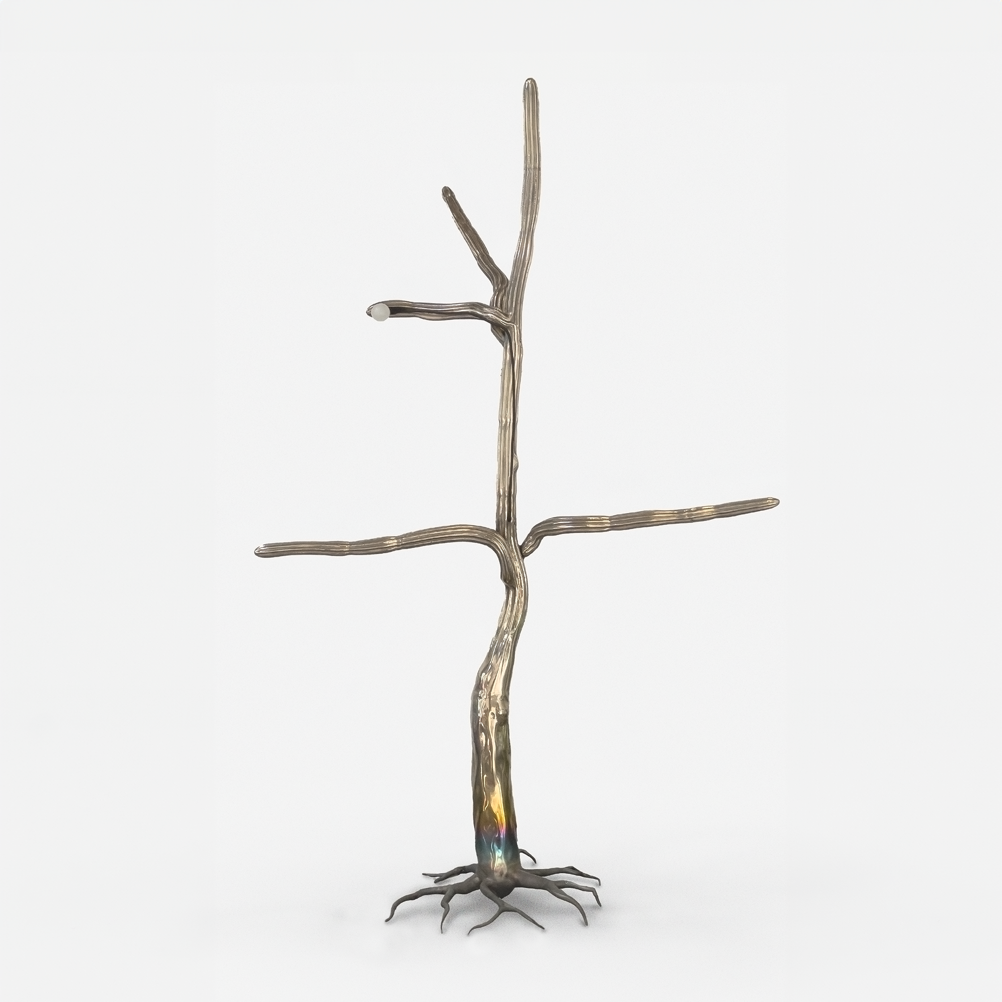 Metal sculpture resembling a tree, with roots, a trunk, and branches, mounted on a white background.