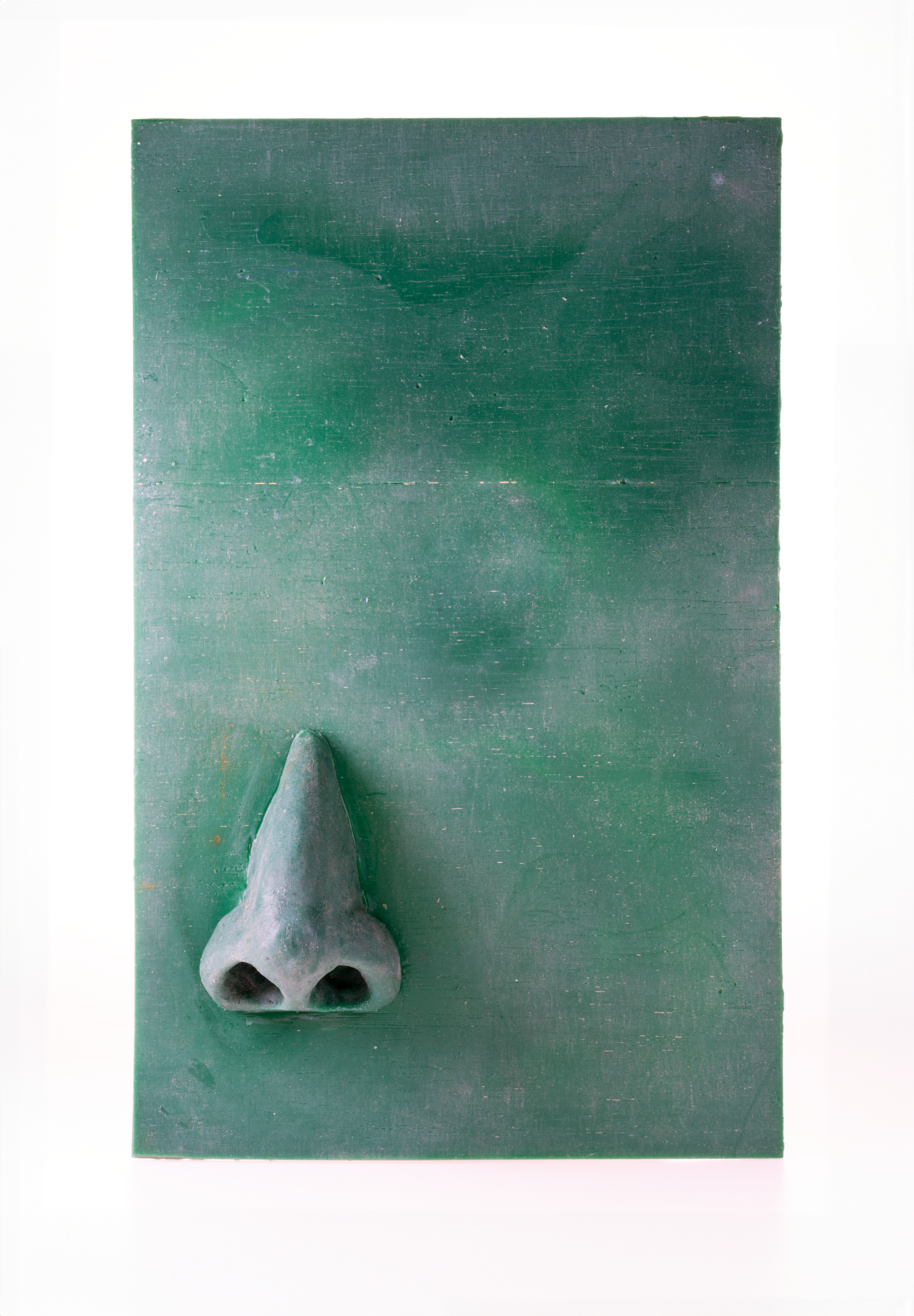 A green board with a 3D nose sculpture attached to it.