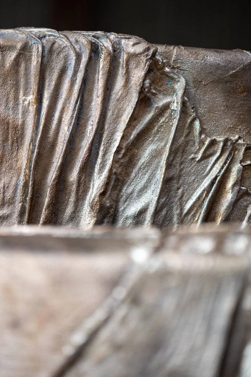 Close-up of a metallic sculpture with textured, layered, and ribbed surface details.