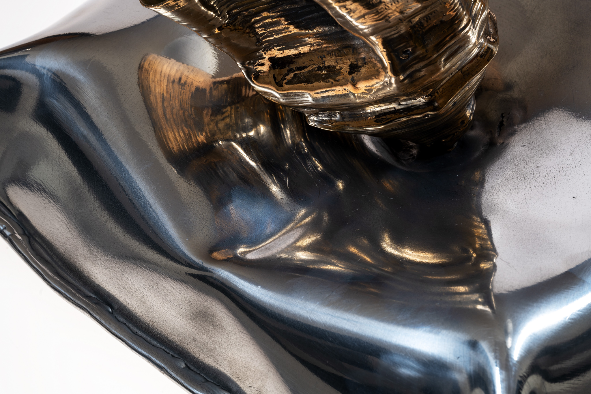Close-up of a metallic sculpture or object with a shiny, reflective surface, showing detailed textures and reflections.