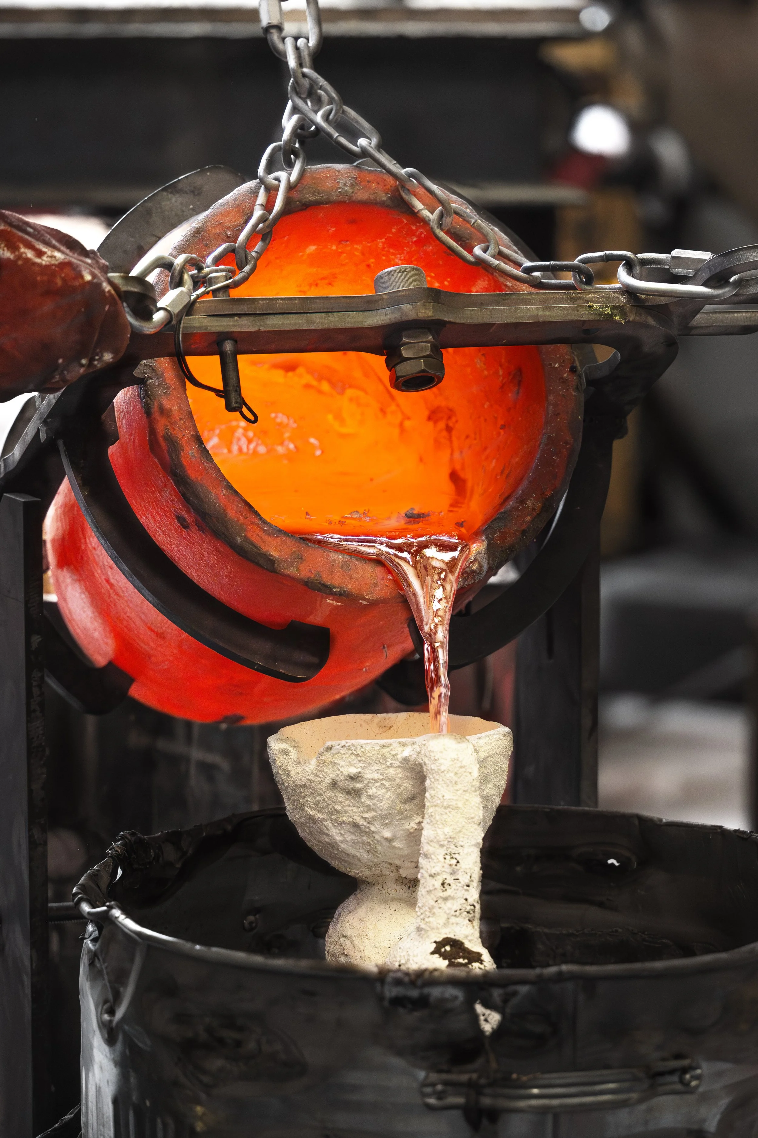 Molten glass being poured from a crucible into a mold in a glassmaking process.