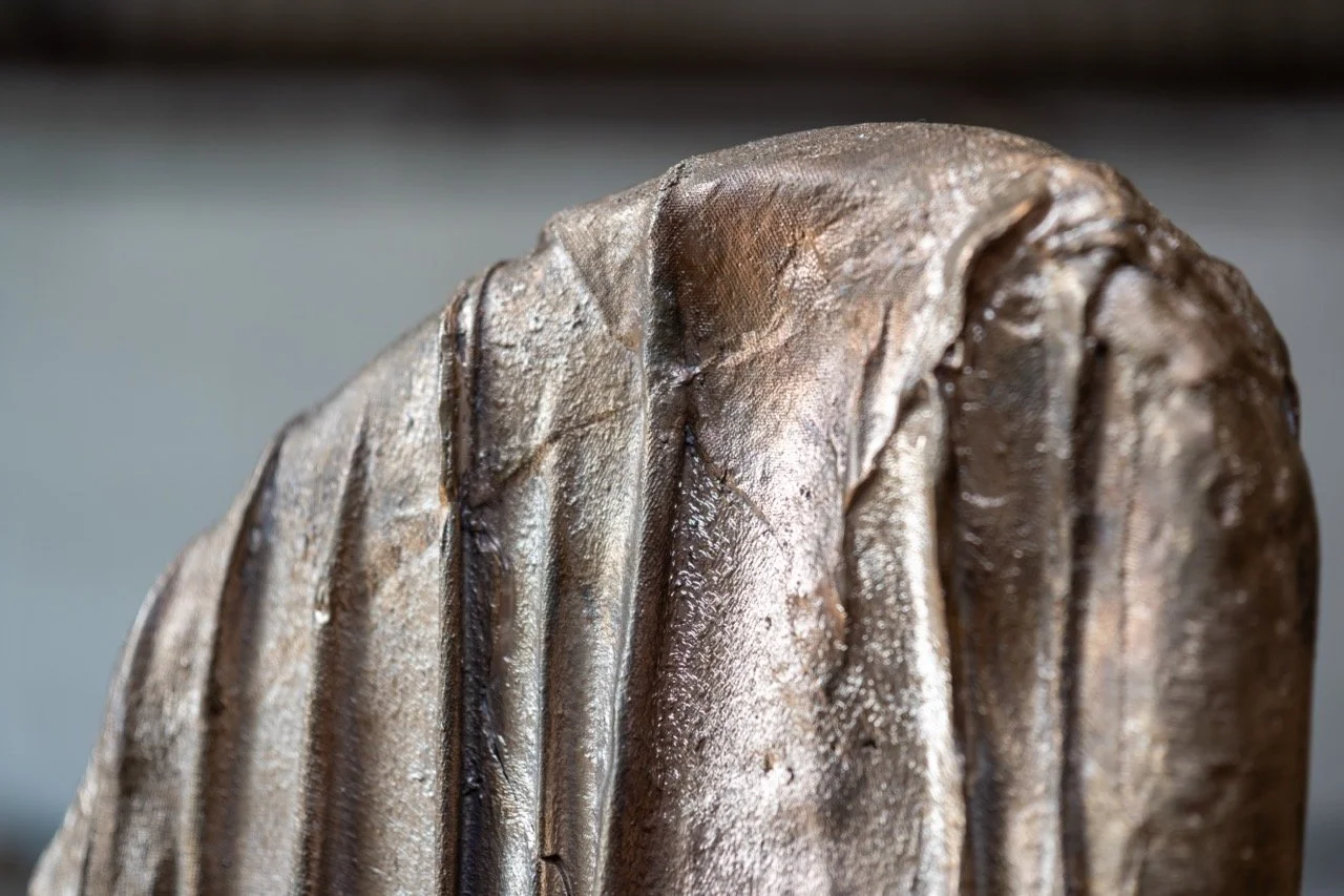 Close-up of a metallic sculpture or object with textured, flowing surfaces.