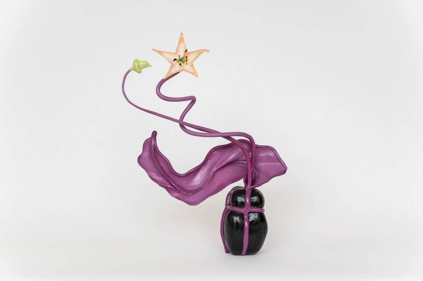 Artistic glass sculpture of a black beetle with purple accents, a purple flowing element, and a flower with a star-shaped blossom on a white background.