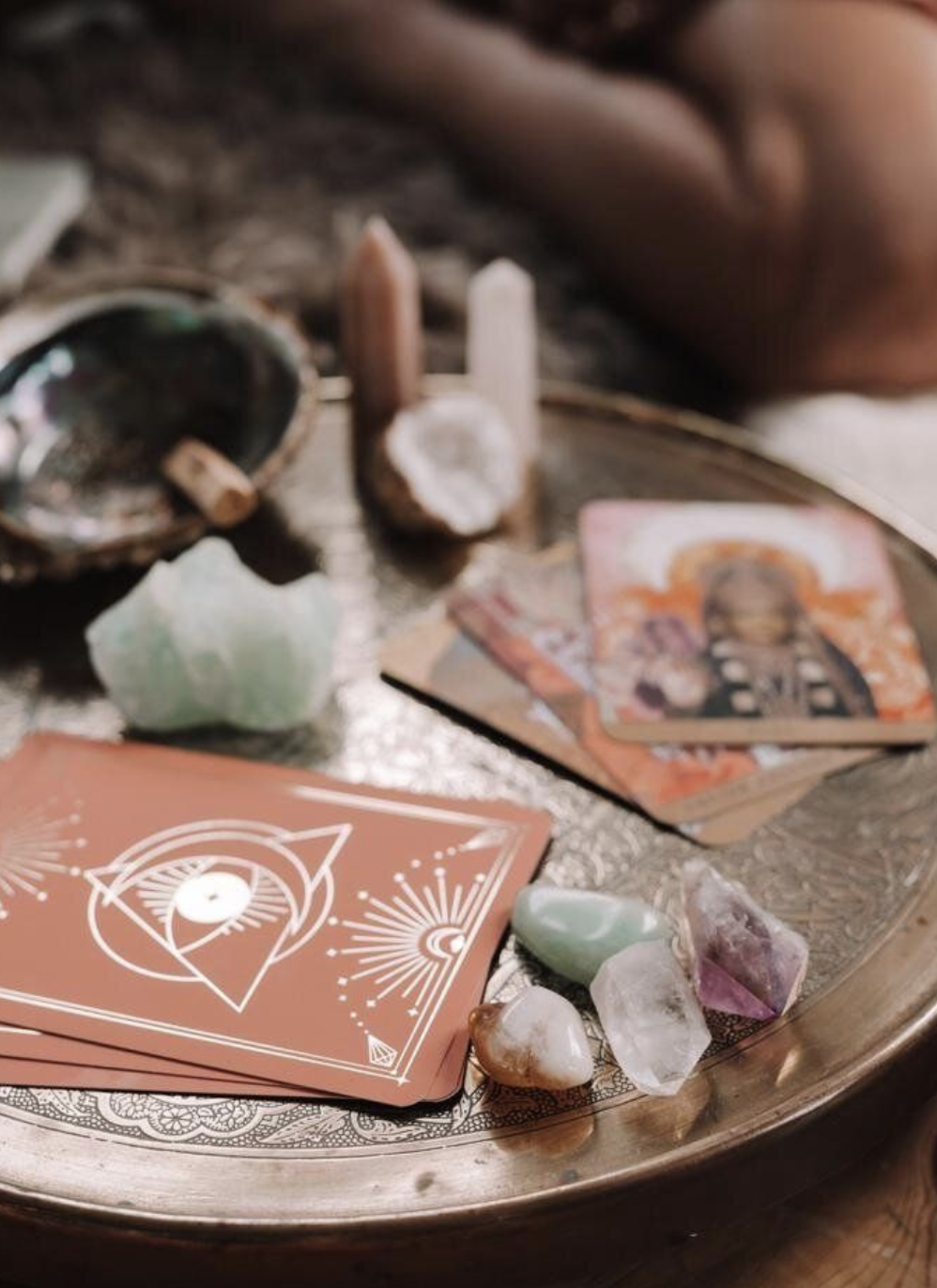 Tarot cards, crystals, and spiritual items arranged on a silver tray for a spiritual or divination practice.