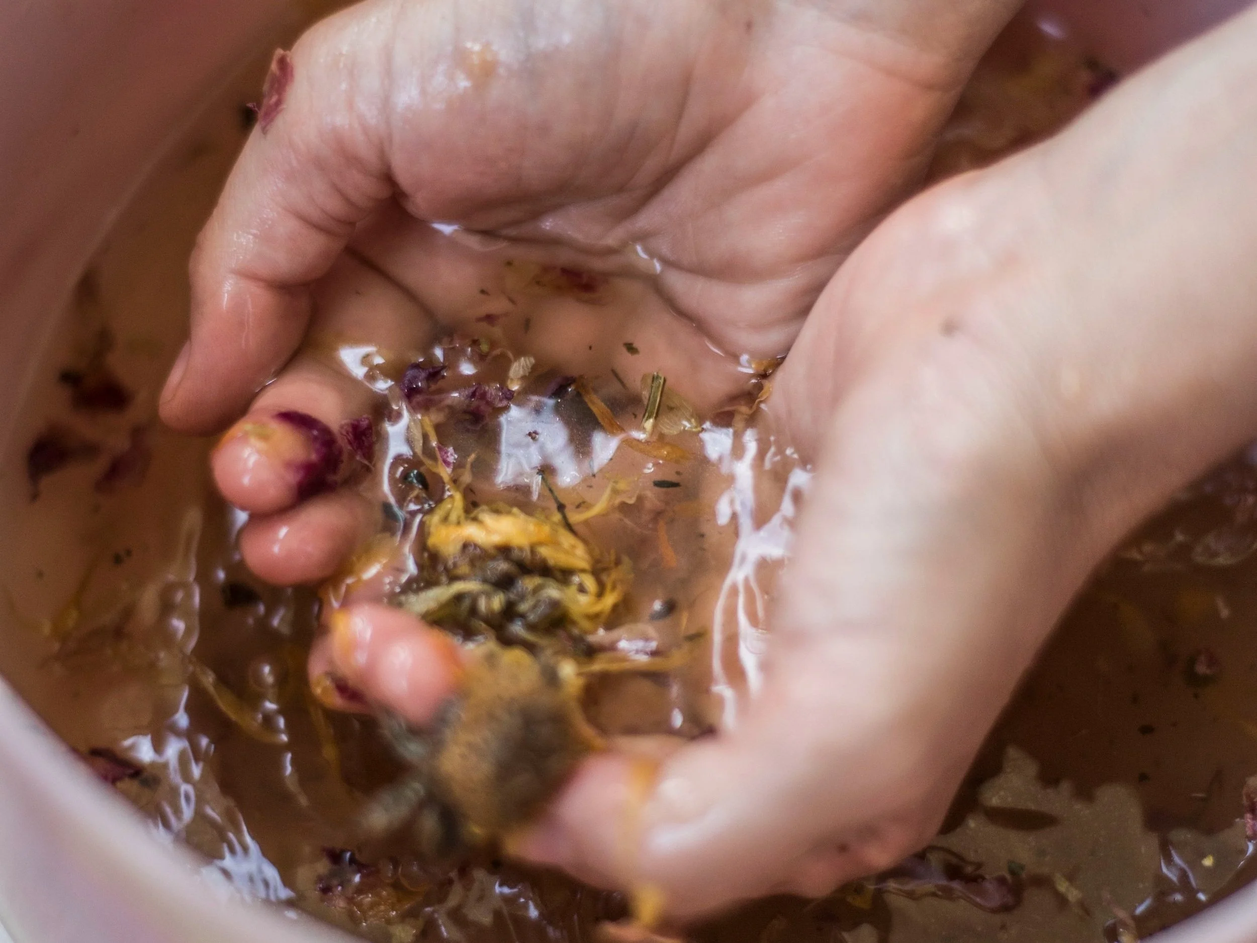 Person mixing or preparing food in a bowl, using hands to stir a mixture that contains herbs and ingredients.