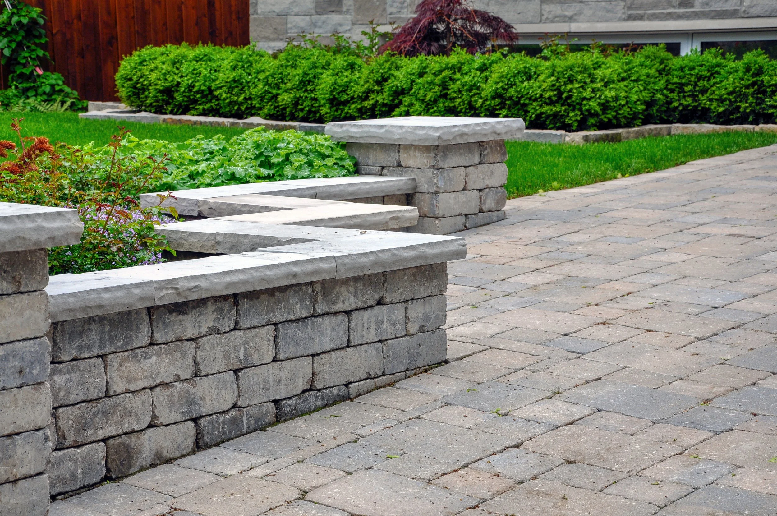 Paver walkway and tiered retaining wall connecting a patio to the lawn in Menomonee Falls, WI