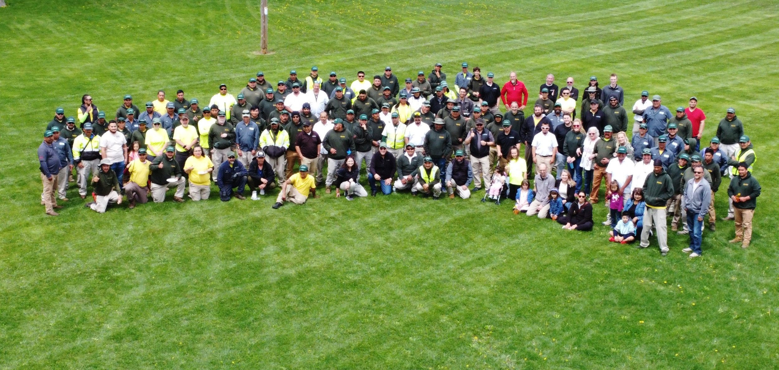 Large group of people gathered on a grassy field, posing for a photo.