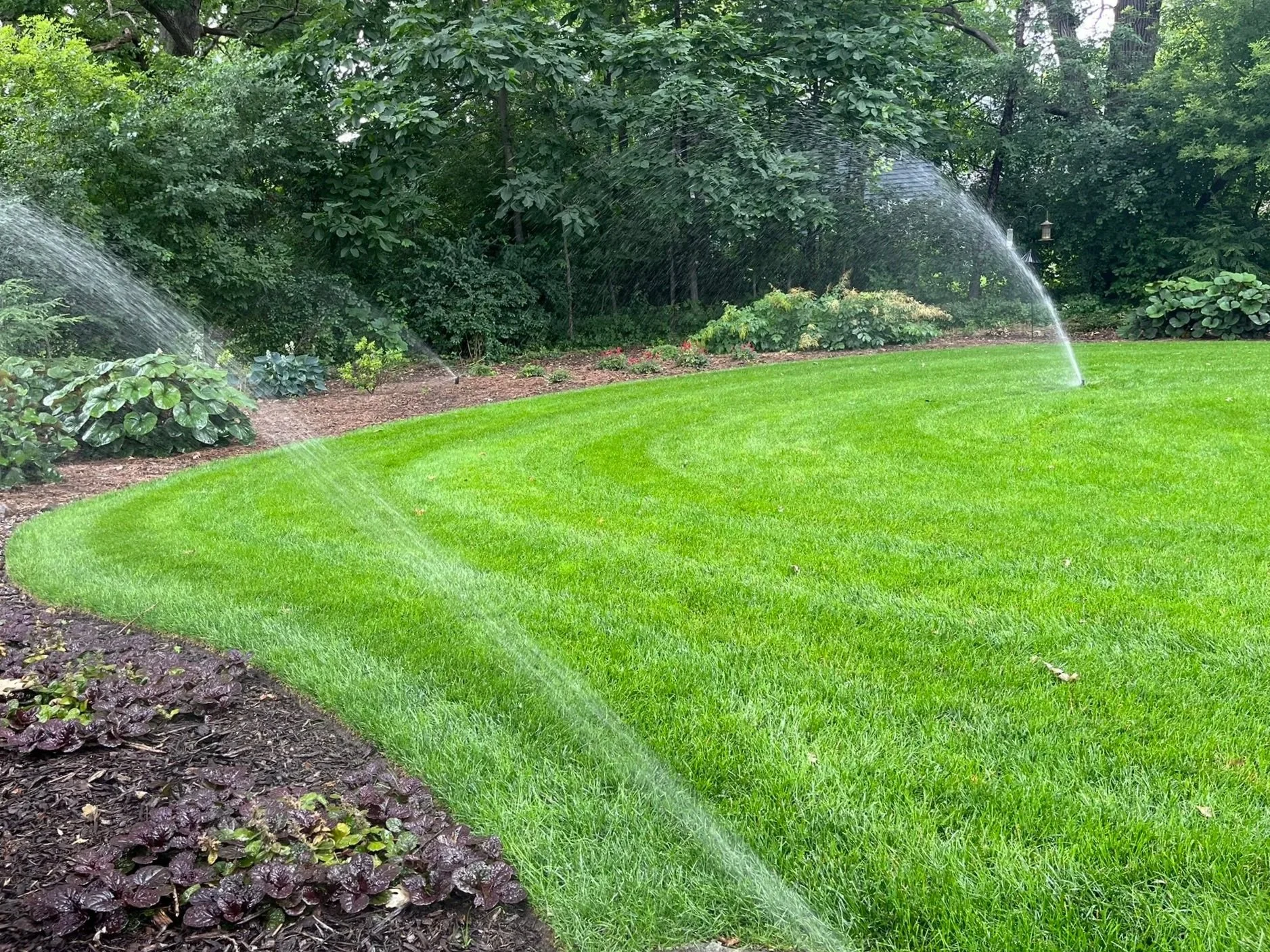 Residential sprinkler system watering a front lawn in Menomonee Falls, WI