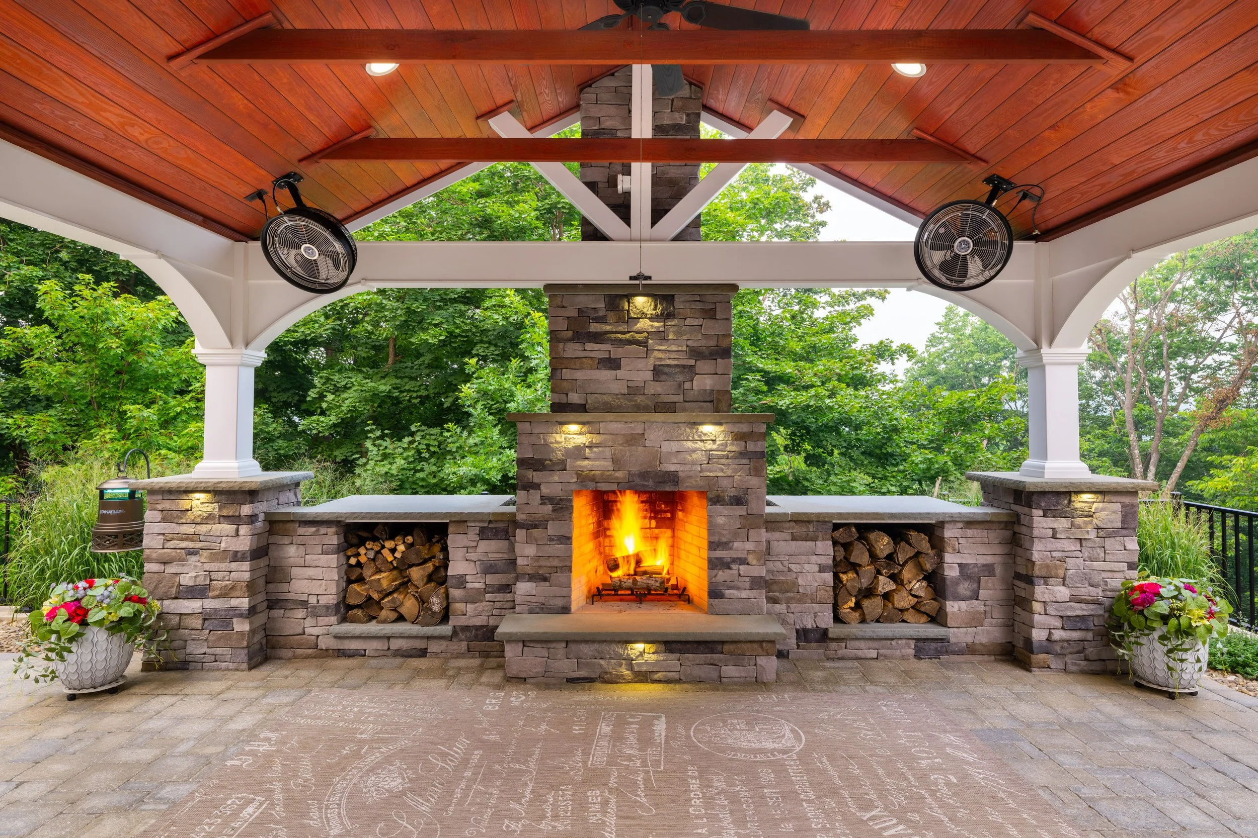 Stone veneer outdoor fireplace with built-in wood storage under a pavilion in Skyline View, PA