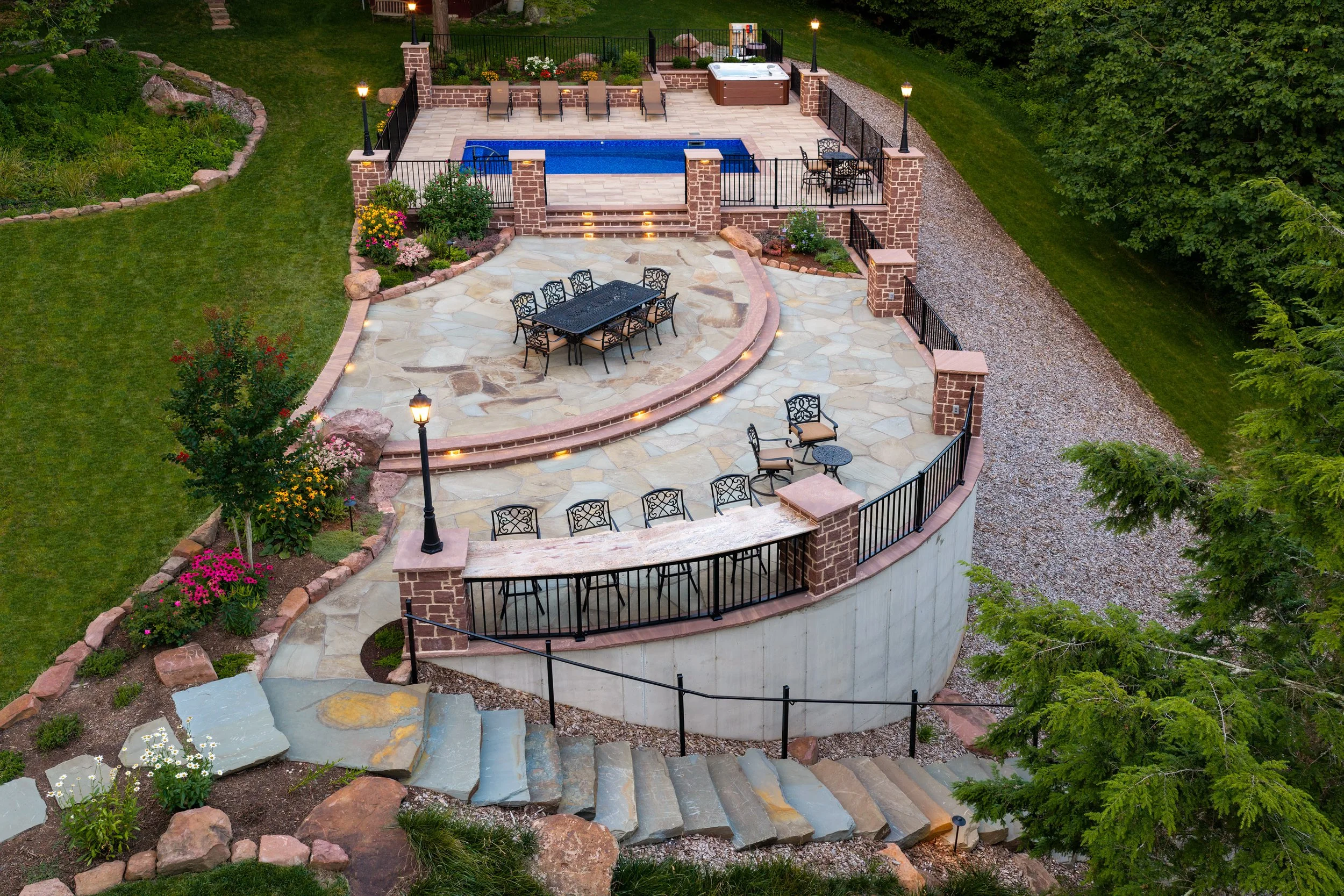 Aerial view of tiered stone walls, pillars and steps on a hillside property.
