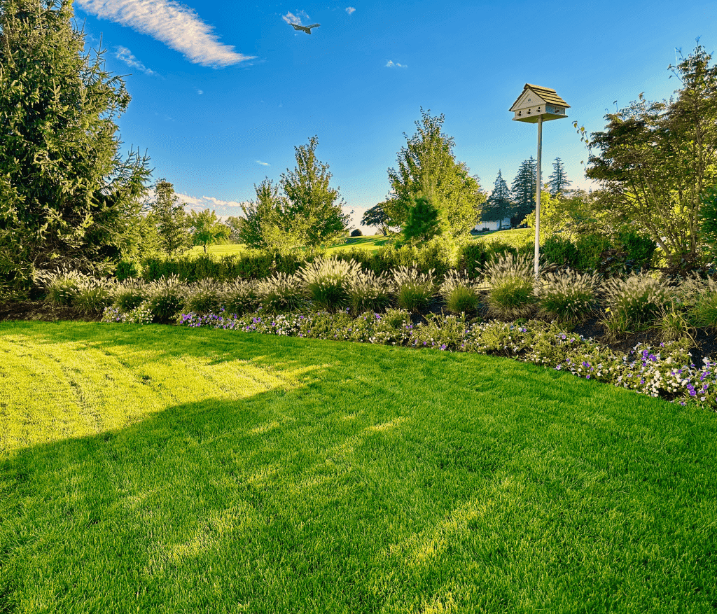 Healthy green lawn with lush shrubbery and a wooden birdhouse in Westchester County, NY