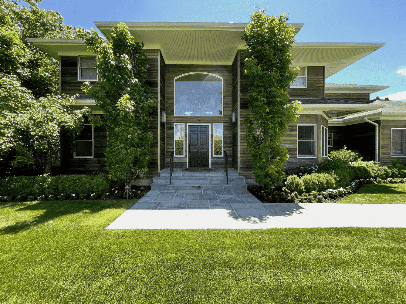 The exterior of a modern home with a paver walkway and beautiful landscaping in Westchester County, NY