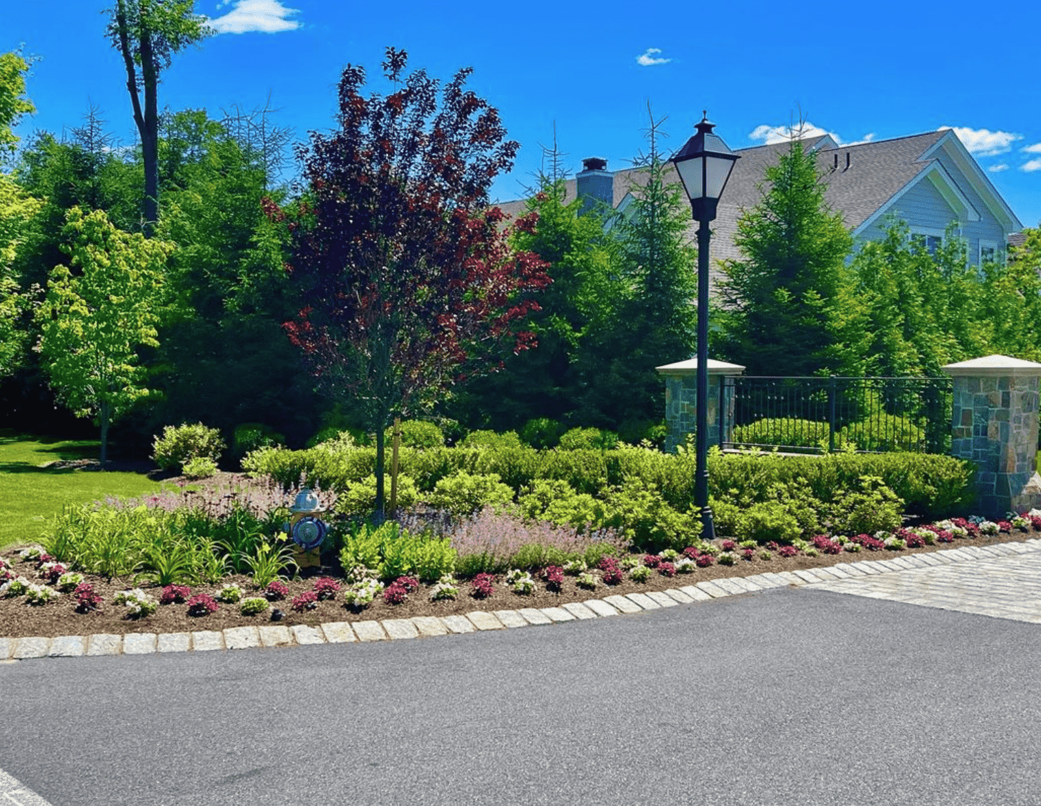A gated community entrance with beautiful landscaping, trees, and flowers in Westchester County, NY