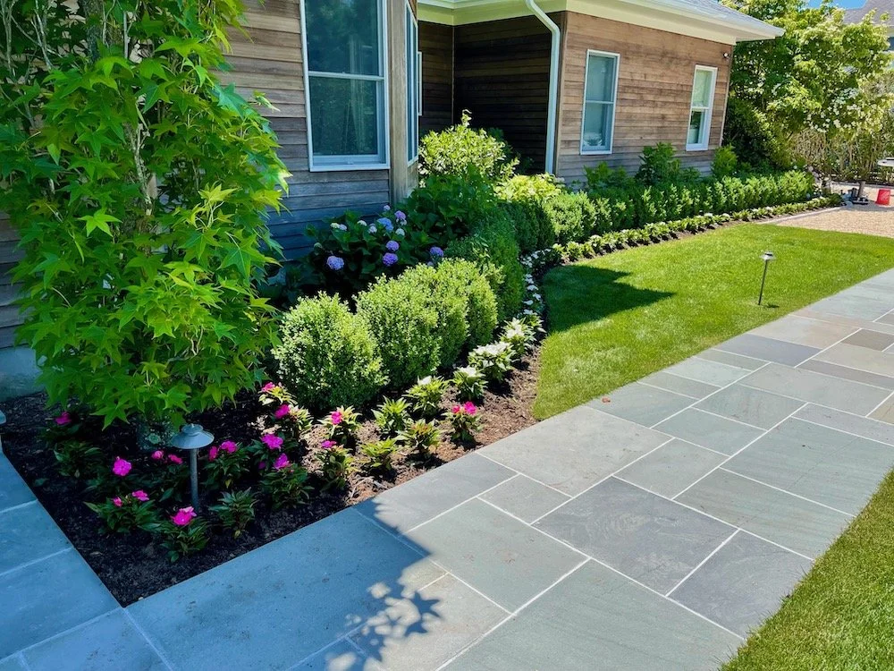 A paver walkway leading up to a residential home with landscaping and plantings in Westchester County, NY