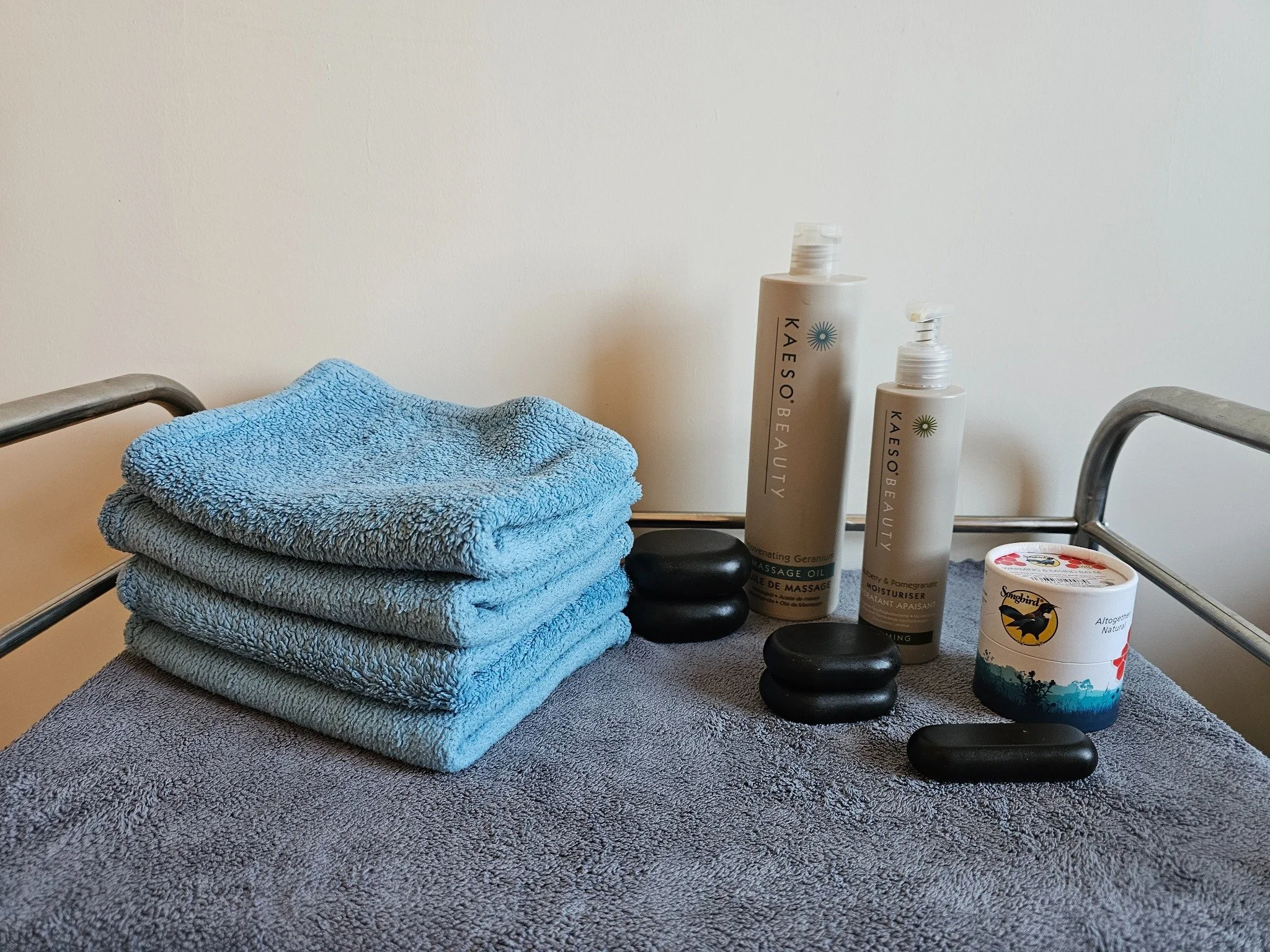 Folded towels, massage products and smooth massage stones prepared at E & T Massage Therapies.