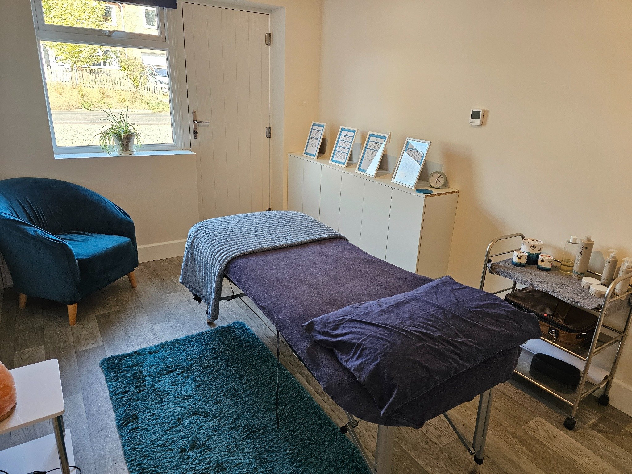 Prepared massage table and client seating inside the E & T Massage Therapies treatment room.