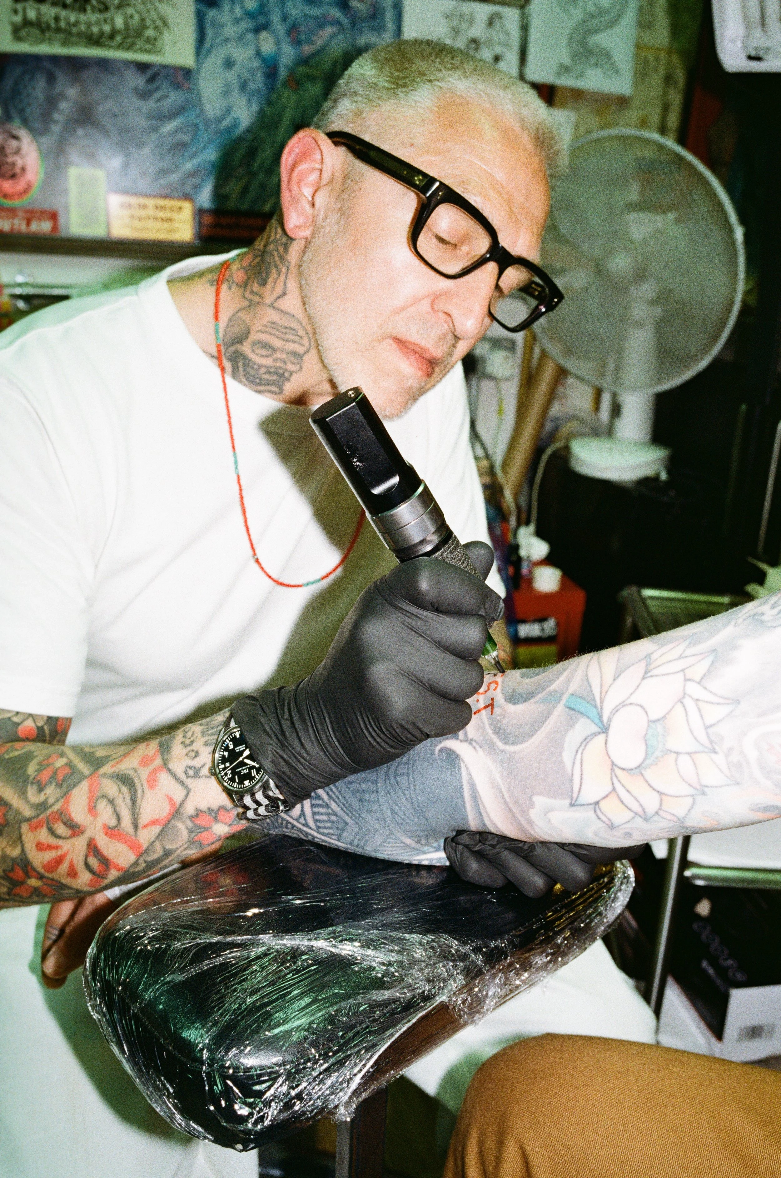 Tattoo artist working on a client's arm in a tattoo studio.