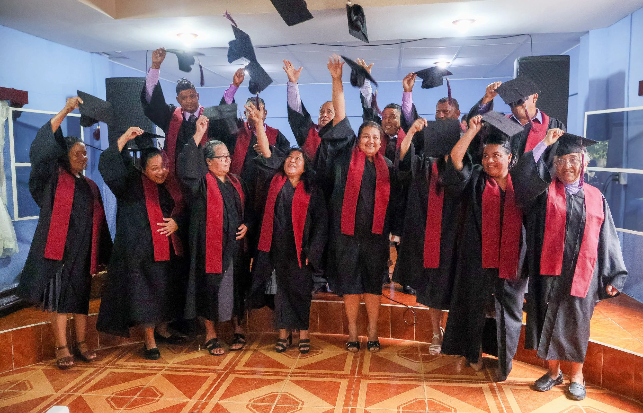 Grupo de graduados lanzando sus birretes en una ceremonia de graduación.