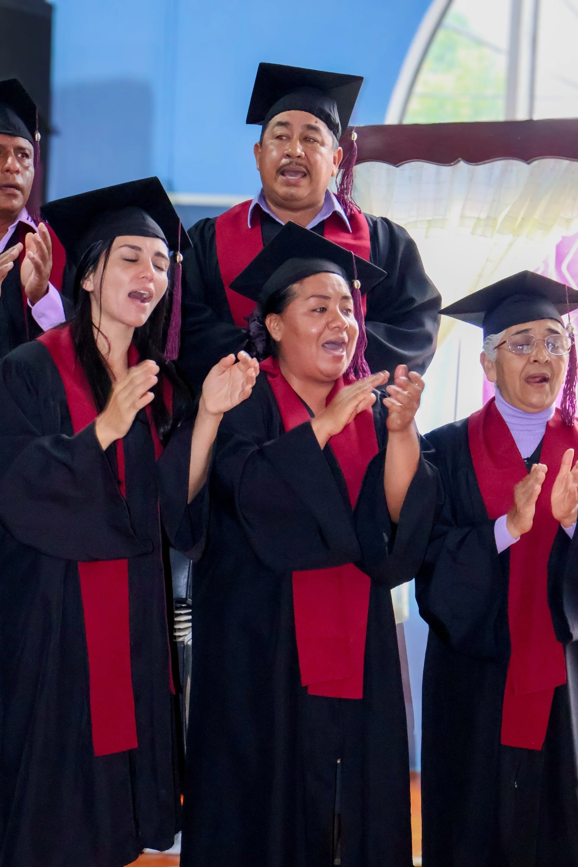 Grupo de graduados con birretes y togas negras, celebrando en una ceremonia académica.