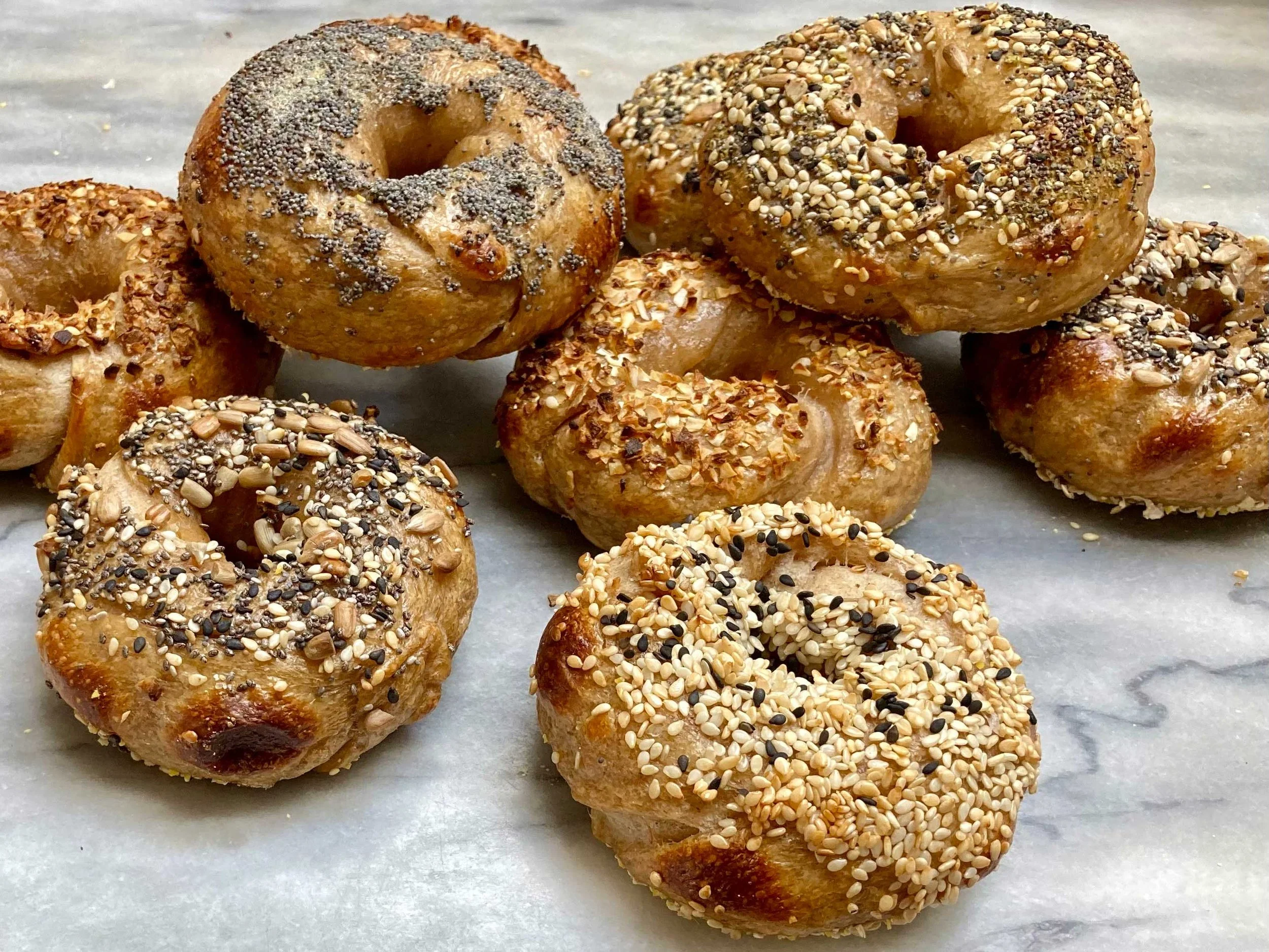 a variety of bagels on a marble countertop