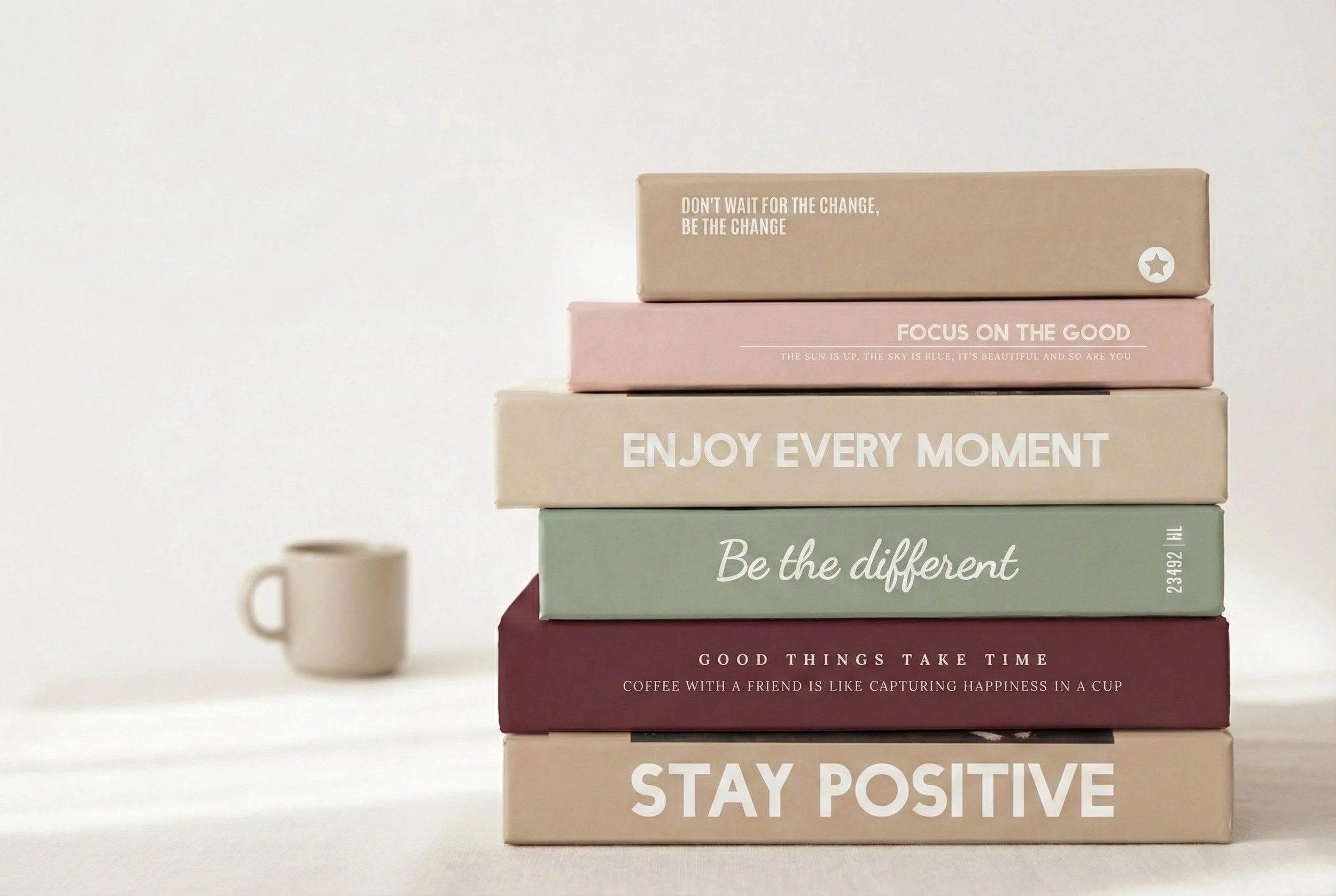 Stack of five pastel-colored boxes with motivational quotes, a coffee mug to the left, and a soft light background.