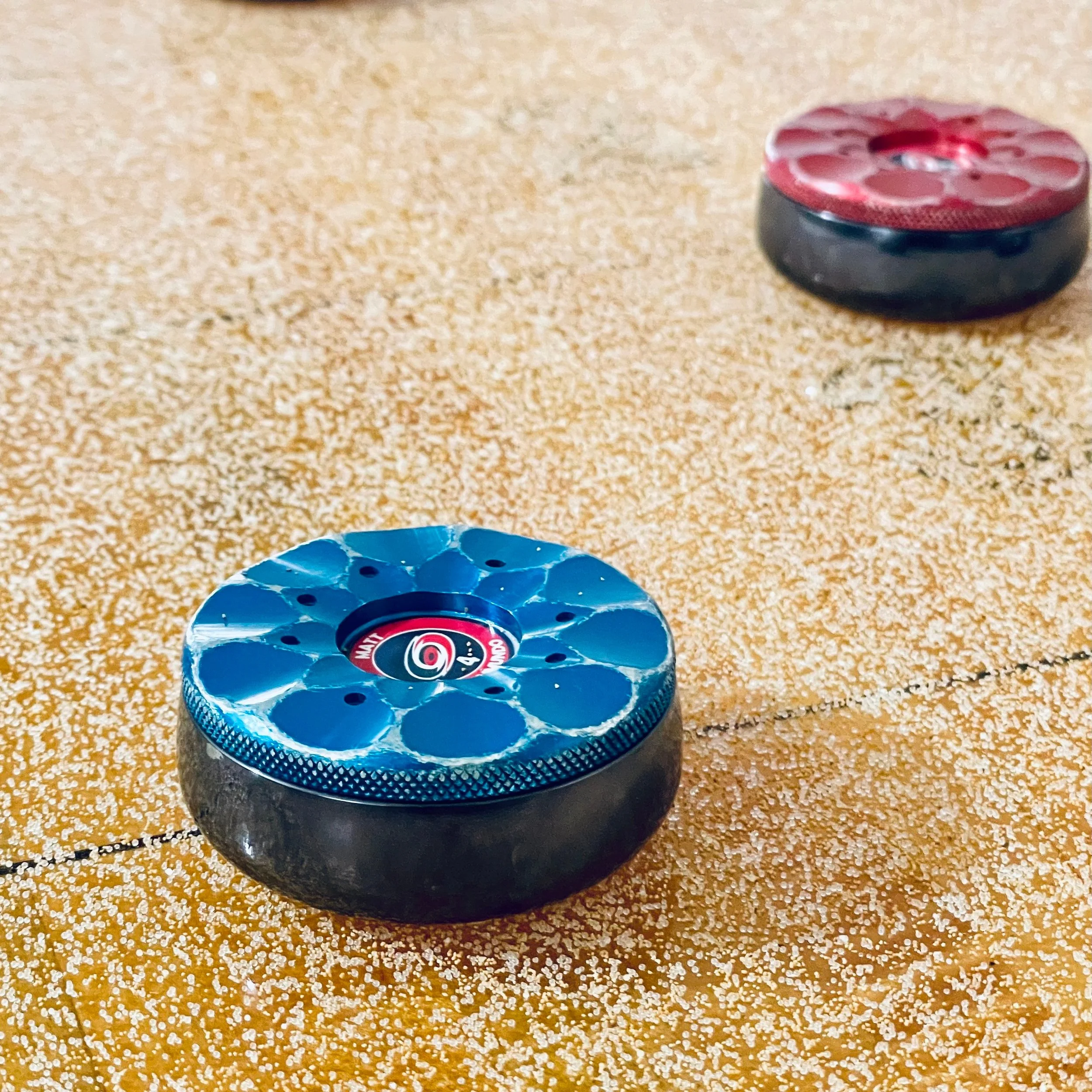 Red and blue shuffleboard pucks on a wooden playing surface