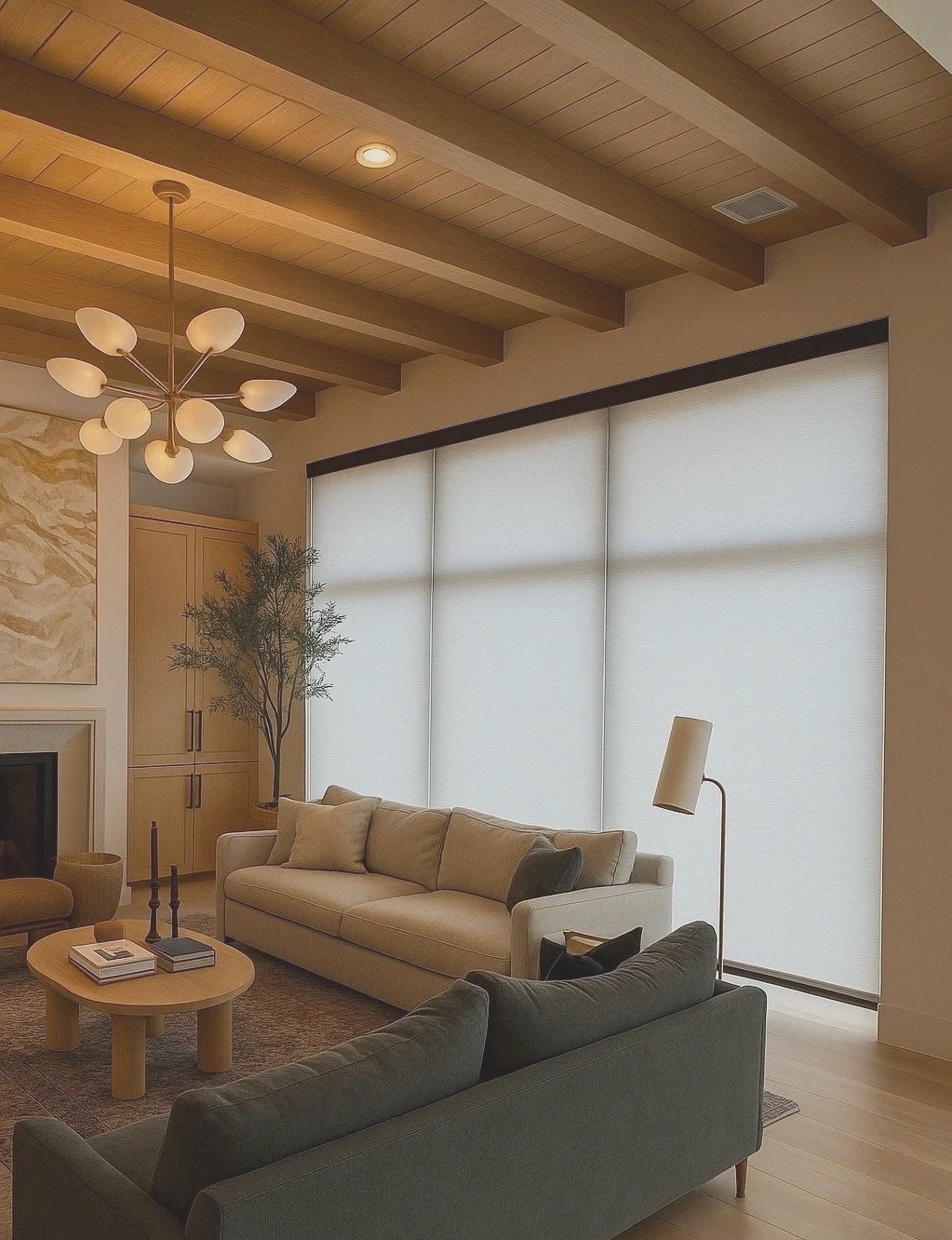Modern living room with beige sofa, dark green armchair, wooden coffee table, large windows with white blinds, ceiling with exposed wooden beams, spiral chandelier, framed artwork, and potted plant.