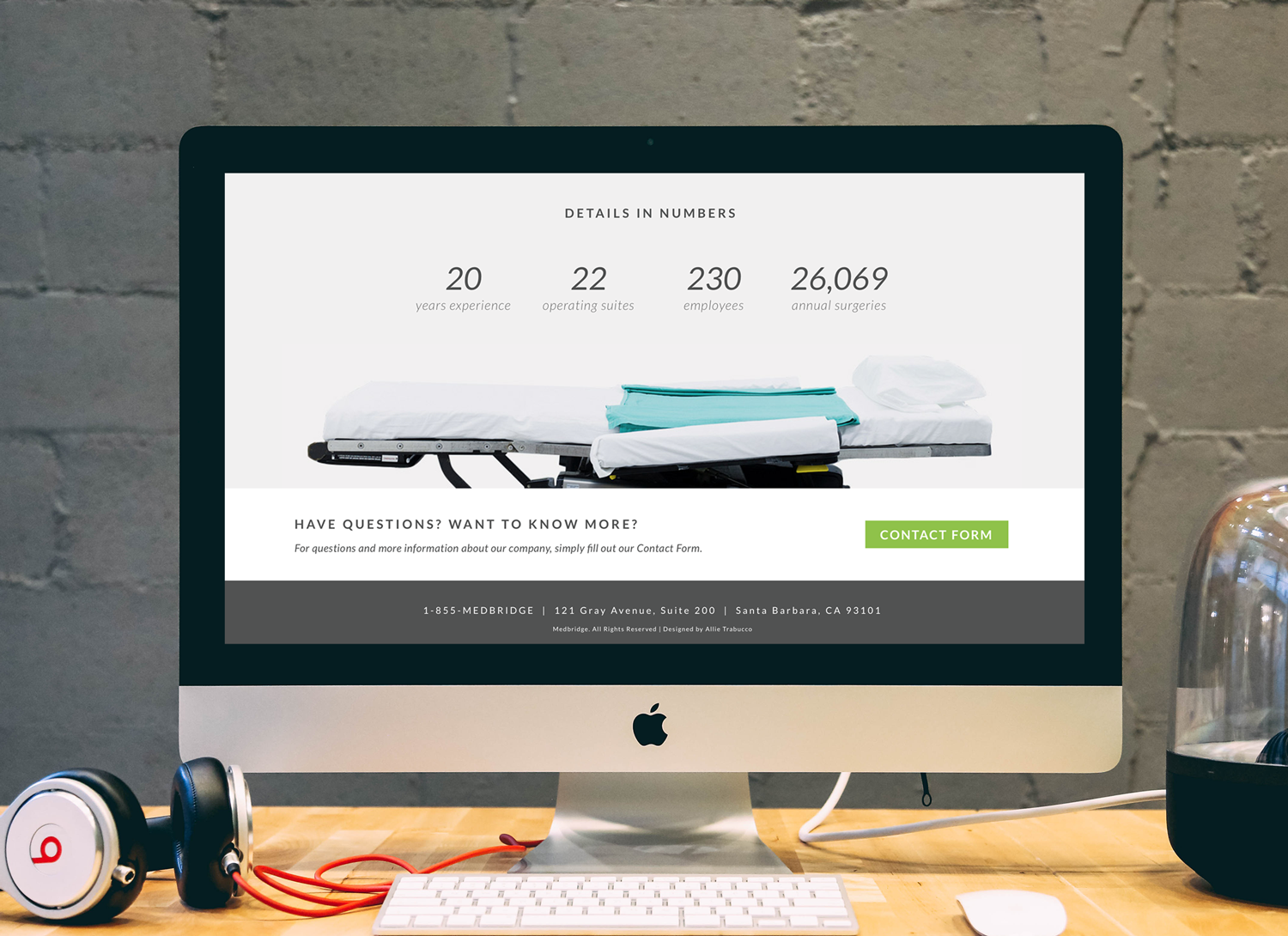 Medical website on a computer screen showing statistics: 20 years experience, 22 operating suites, 230 employees, 26,069 annual surgeries, and a contact form button. Background includes Beats headphones on a desk.