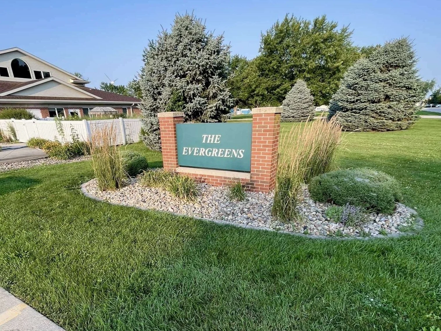 Landscaped entrance bed with ornamental grasses and rock at The Evergreens community sign