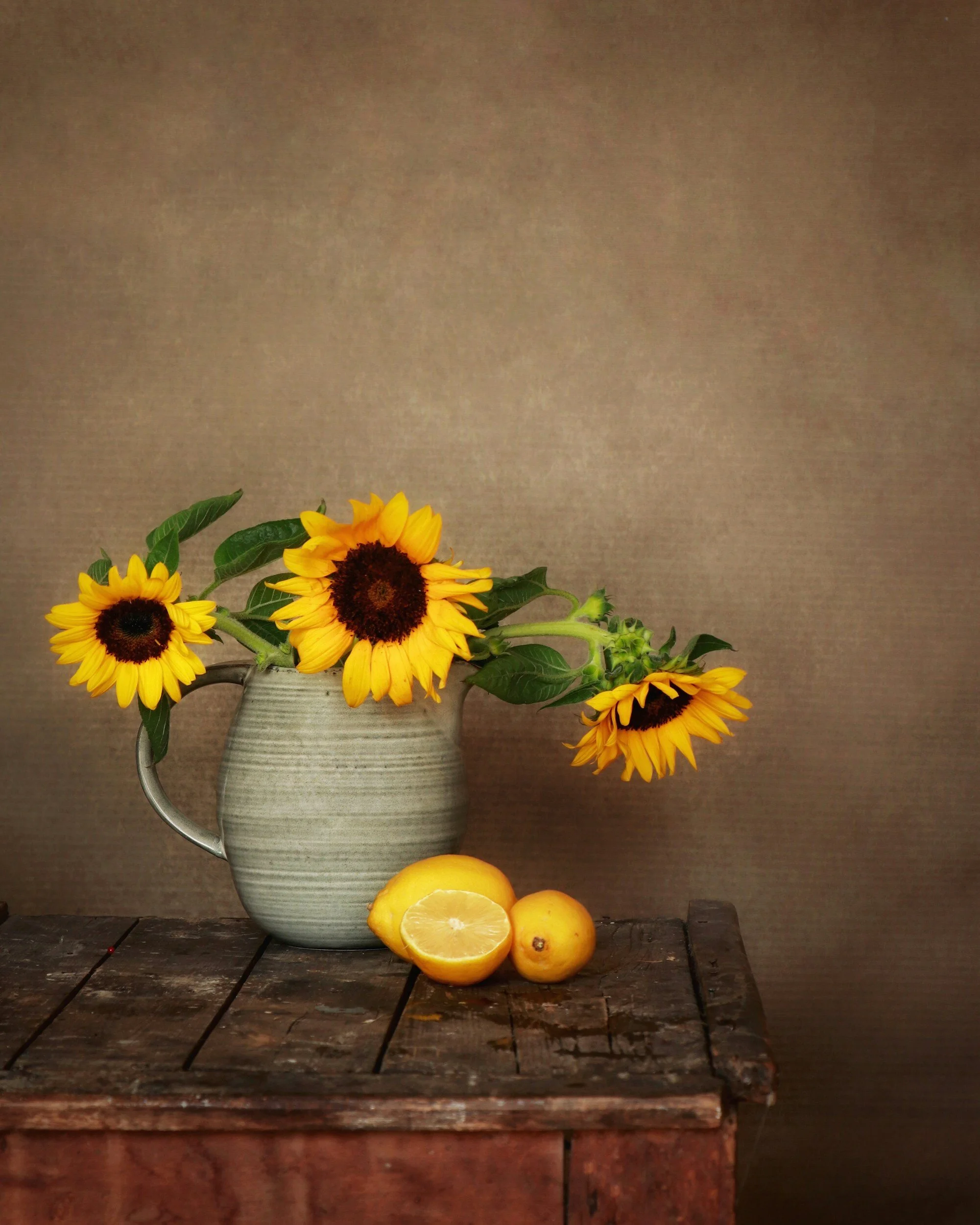 Beautiful still life of sunflowers in a stoneware pitcher on wooden tablInterior Decorator Airbnb Vacation Rental Vrbo Home Staginge with lemons