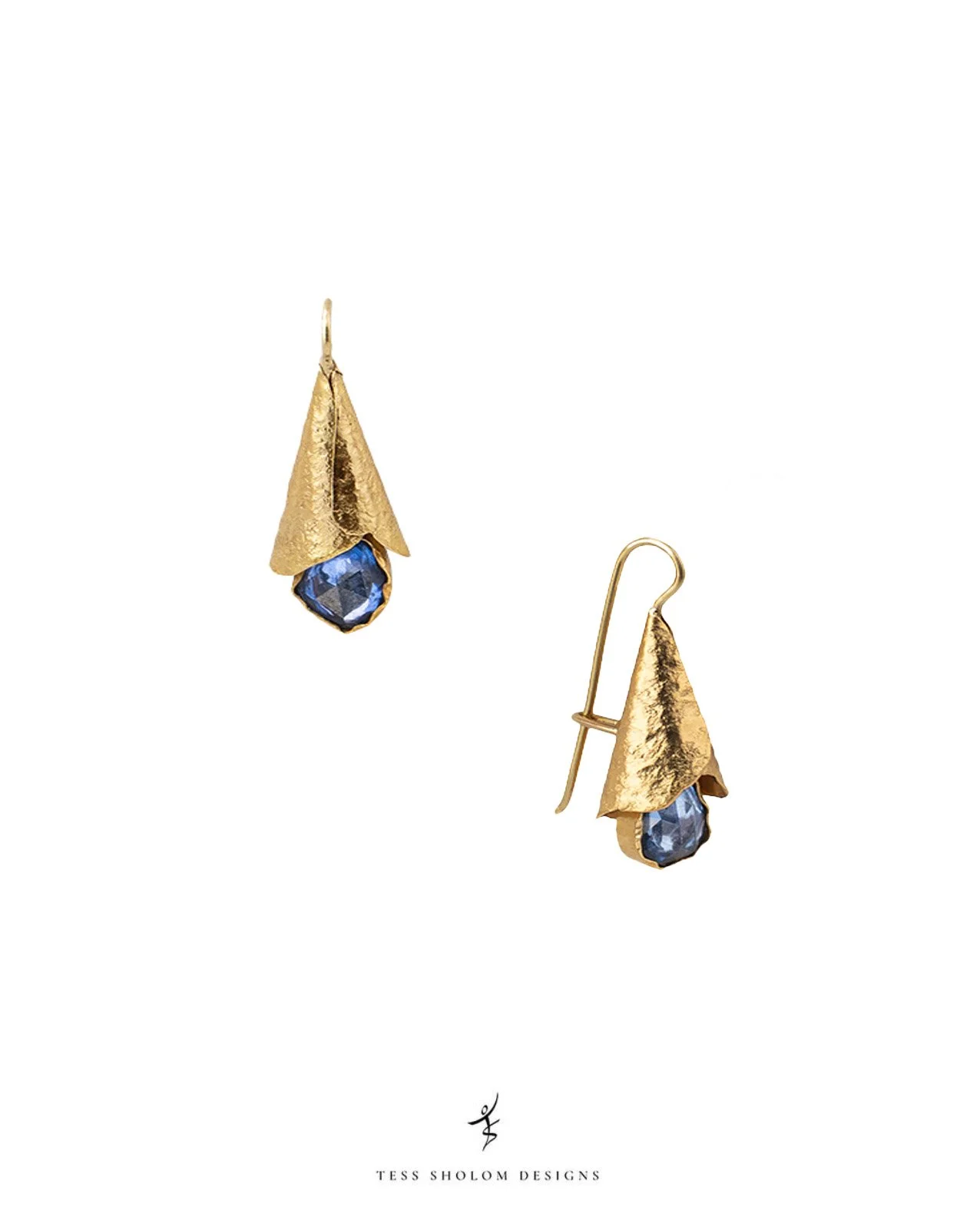 Gold earrings with blue gemstones against a white background, featuring the text 'Tess Shalom Designs' at the bottom.