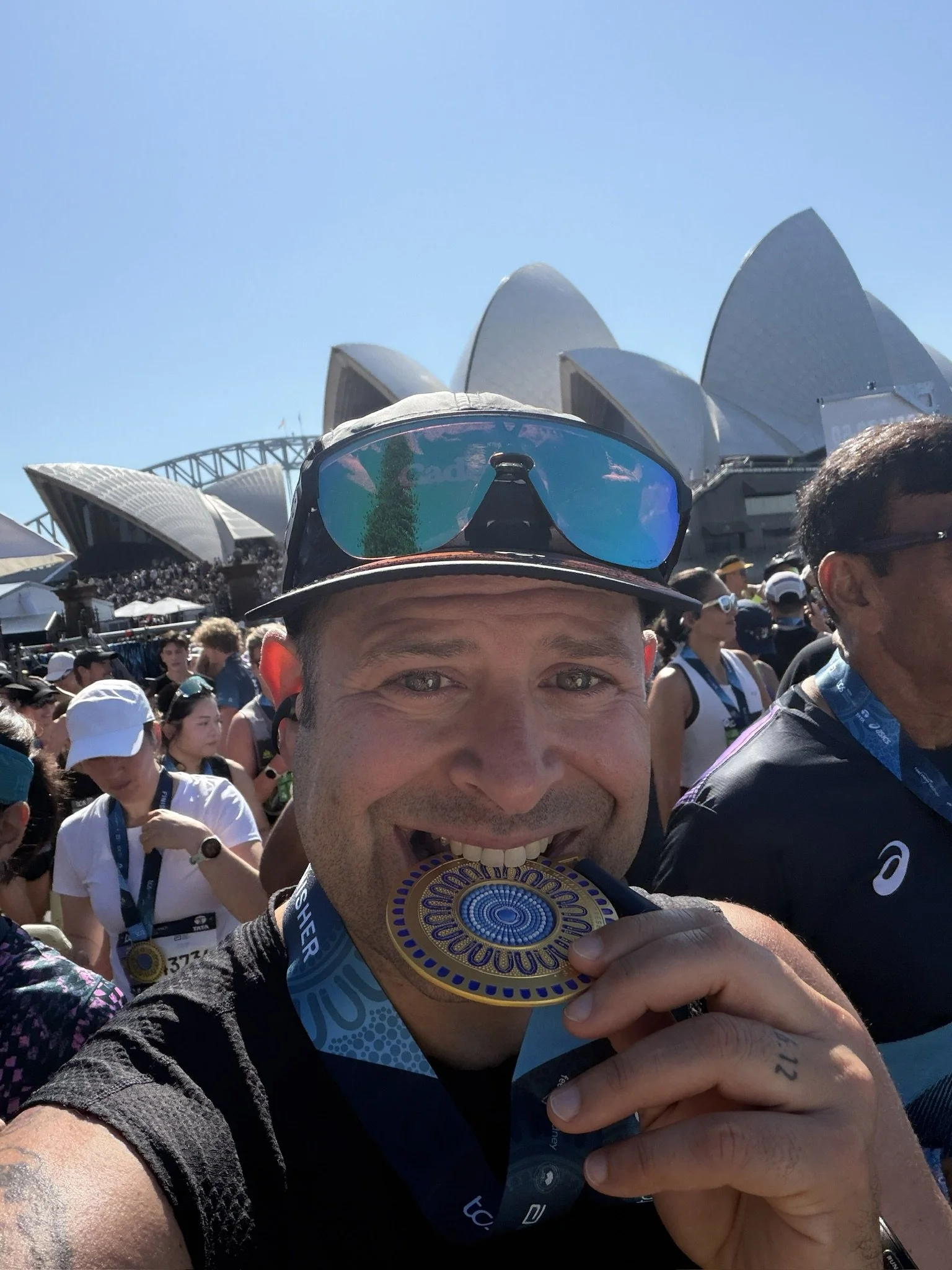 James biting his Sydney Marathon medal in front of the Opera House