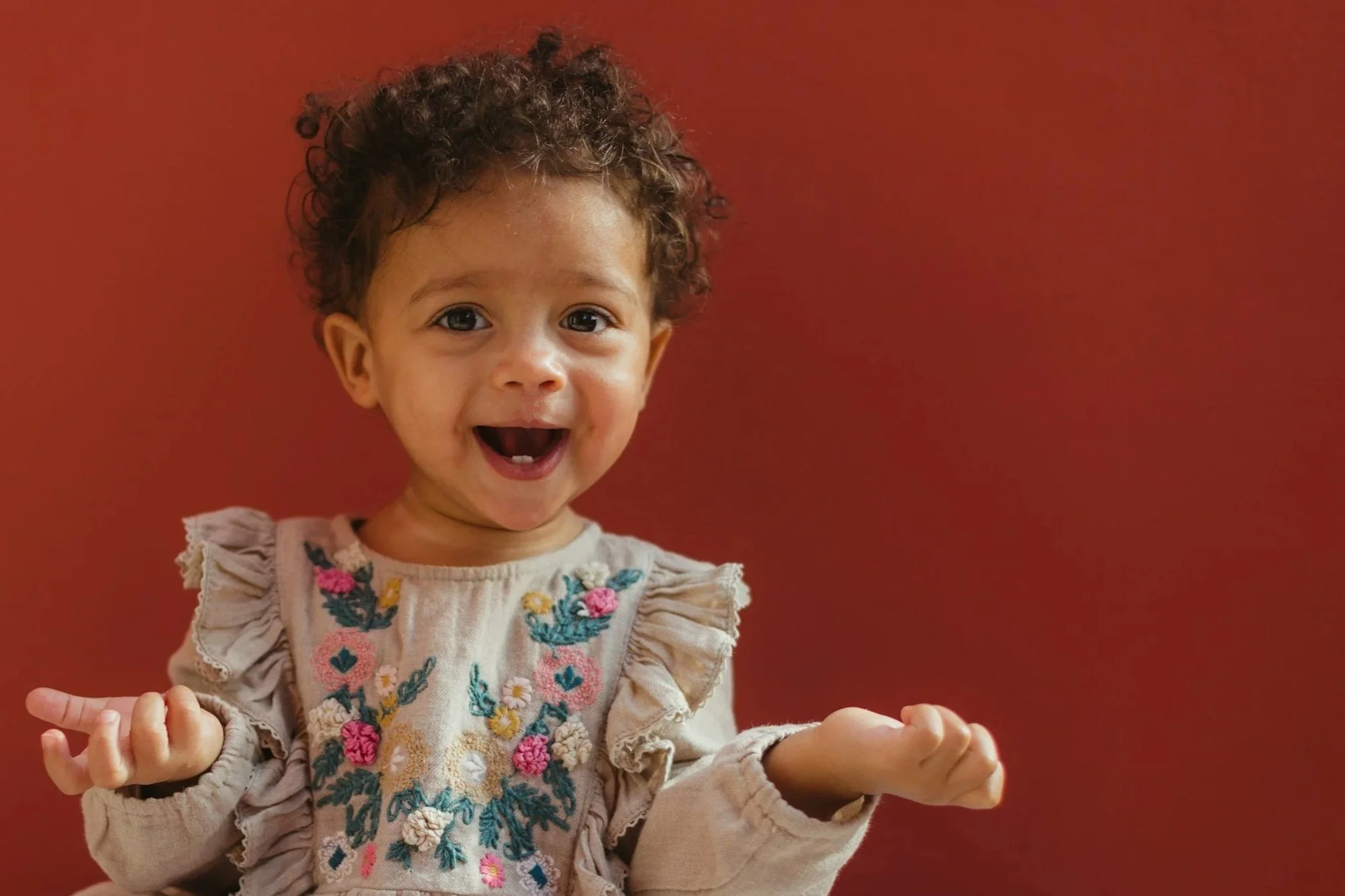 a cute biracial baby looks happy but confused