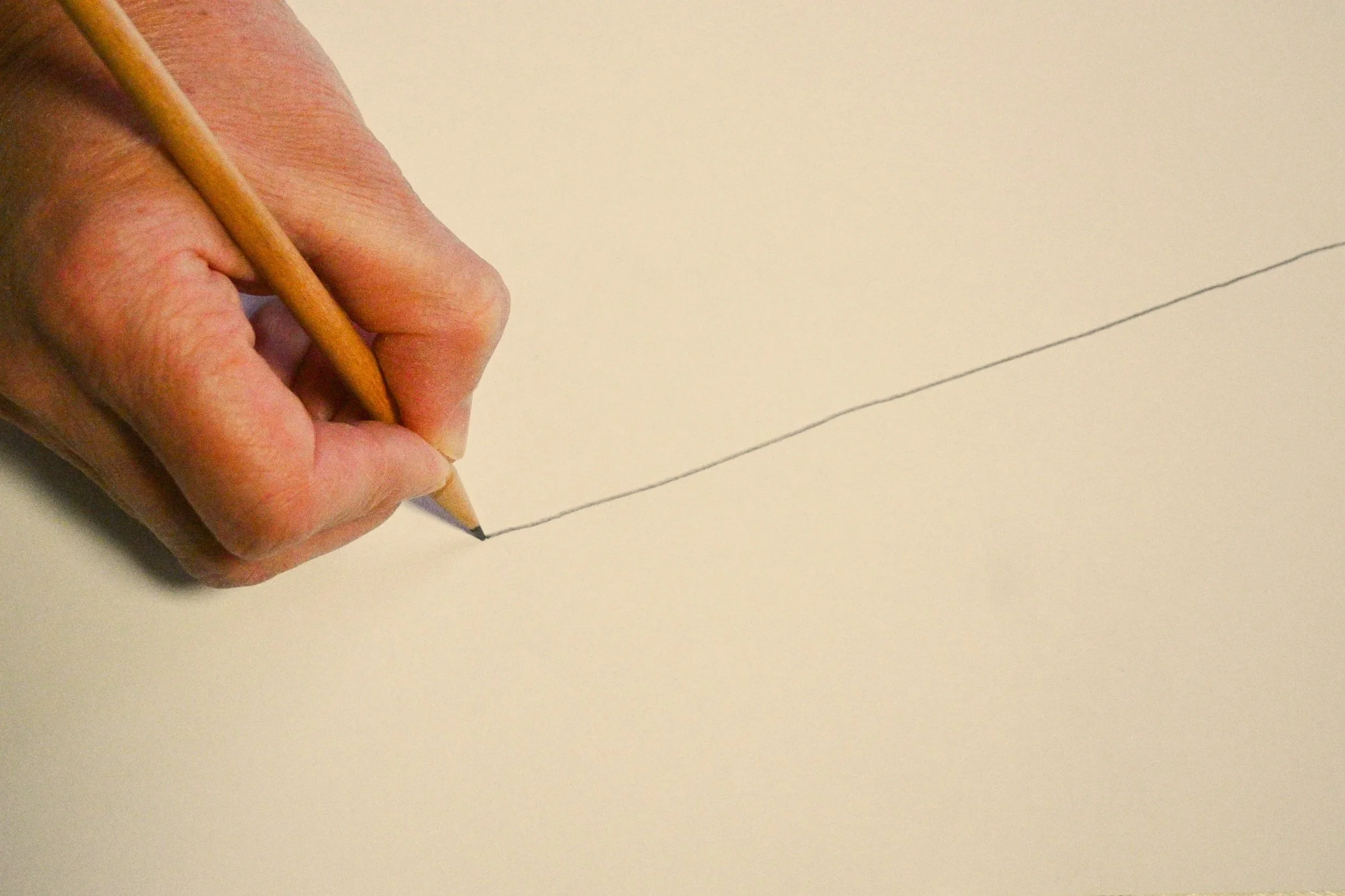 hand drawing a line on paper with a pencil