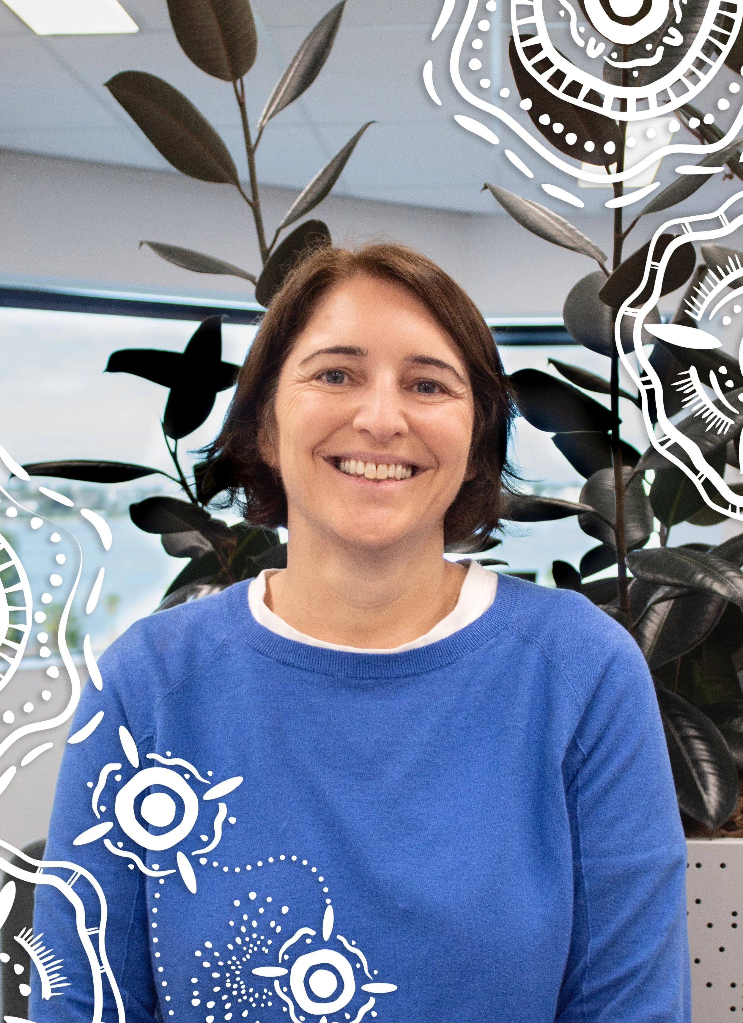 Smiling woman with short brown hair wearing a blue sweatshirt, sitting in front of large dark green plants, with decorative white doodle overlay.