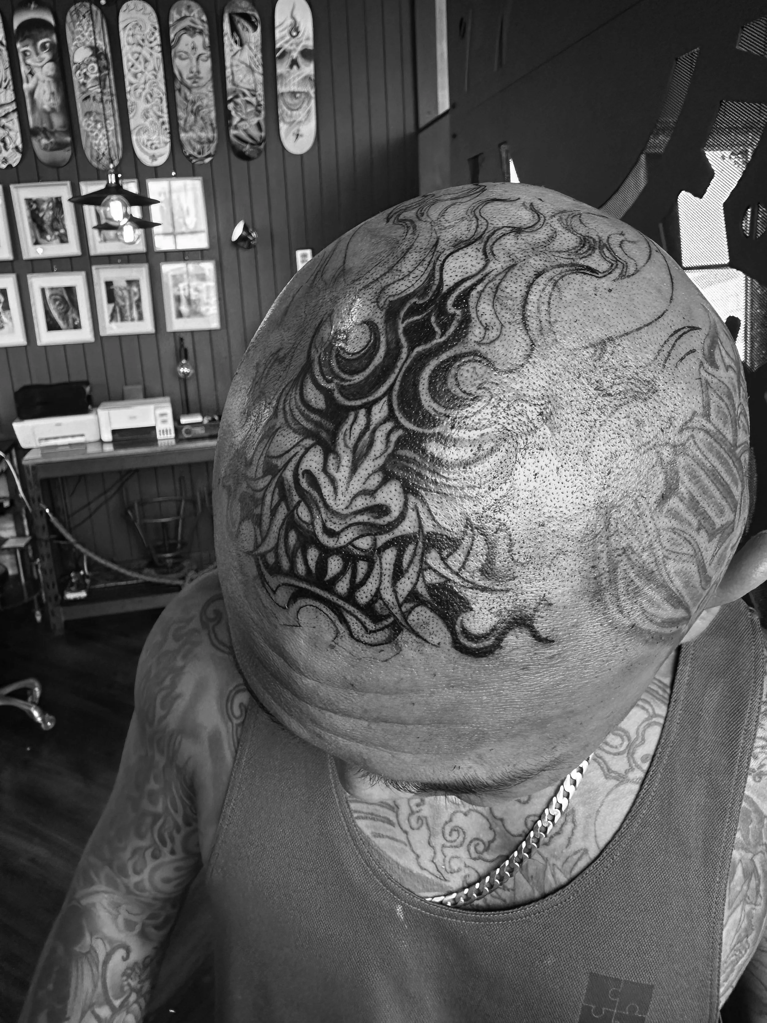 Tattooed person with a dragon tattoo on their head and tattoos on their arm inside a tattoo parlor.