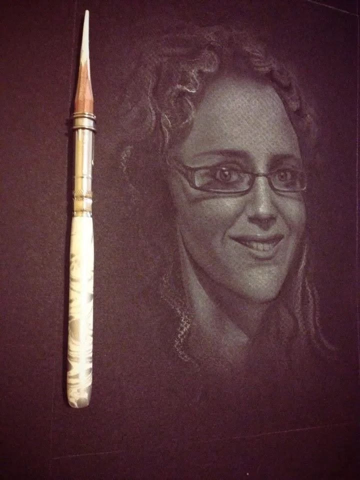 Pencil drawing of a woman with curly hair and glasses, smiling.