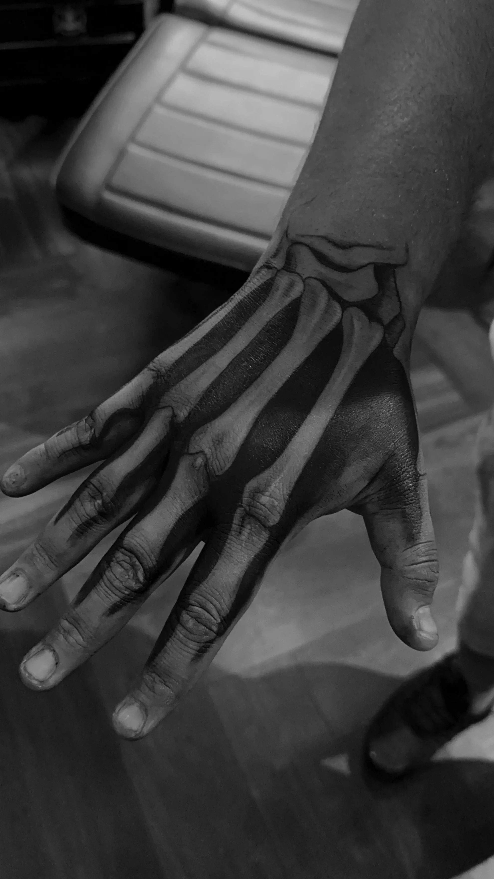 A person with a realistic skeleton tattoo on their hand and wrist, extending to their forearm.