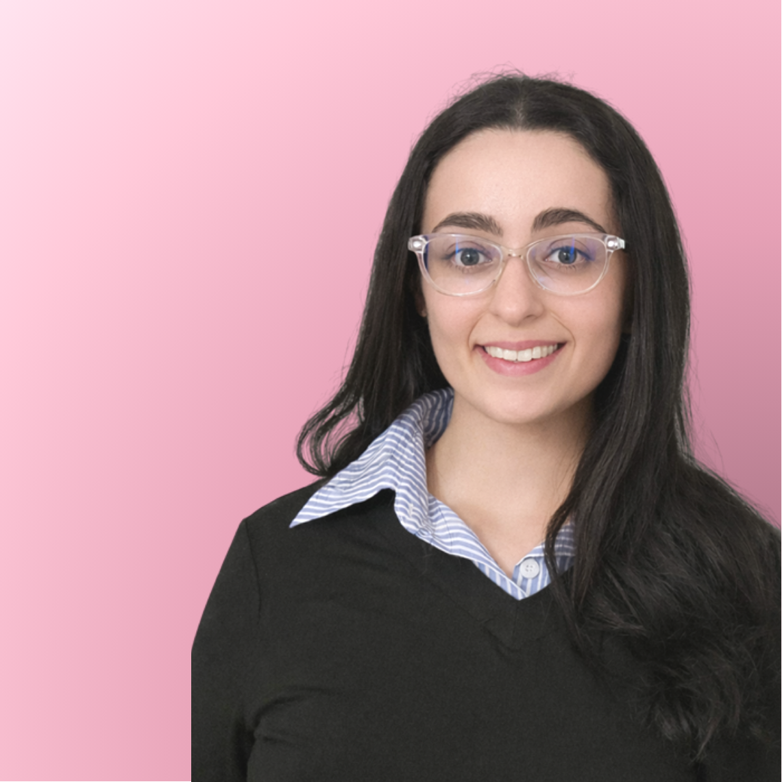 A young woman with long dark hair, wearing glasses, a striped collared shirt, and a black sweater, smiling against a pink background.