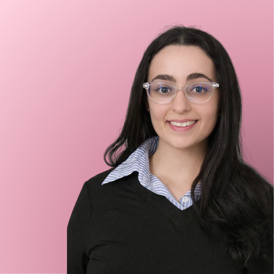 A young woman with long dark hair, wearing clear glasses, a black sweater, and a collared blue and white striped shirt, smiling against a pink background.