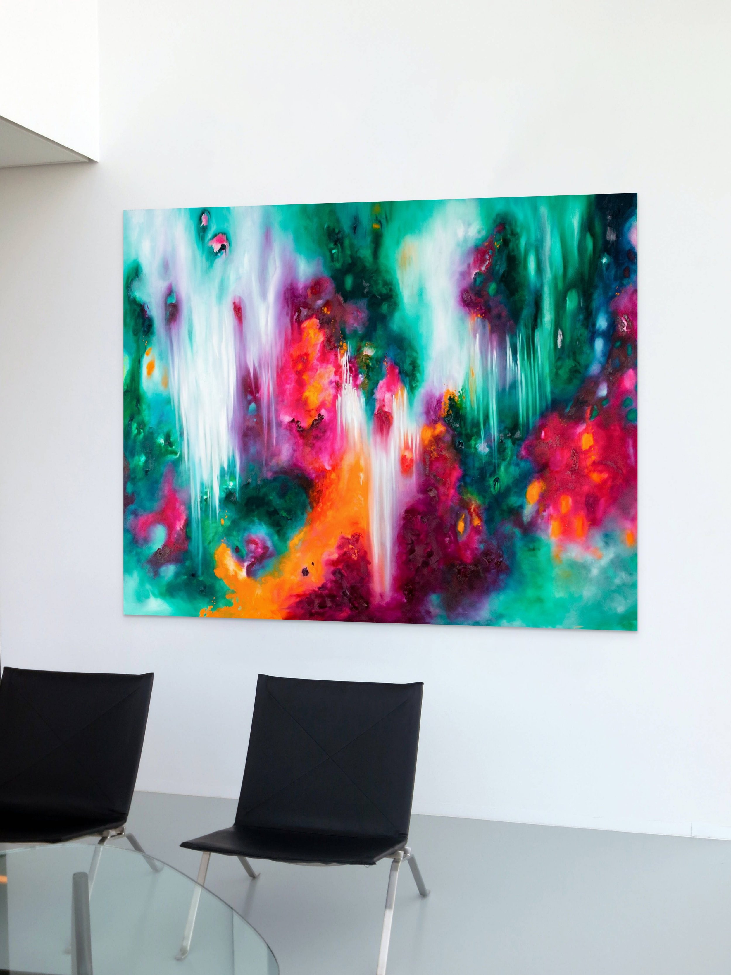 Colorful abstract forest painting with swirling green, pink, orange, purple, and blue hues hanging on a white wall in a modern art gallery.