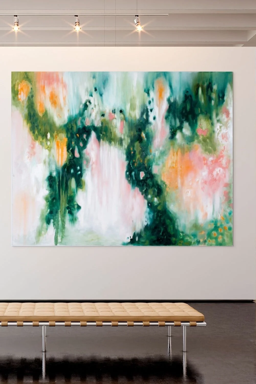 Abstract forest painting in an art gallery, with colors of green, pink, orange, and white, hung on a white wall above a beige lounge bench.