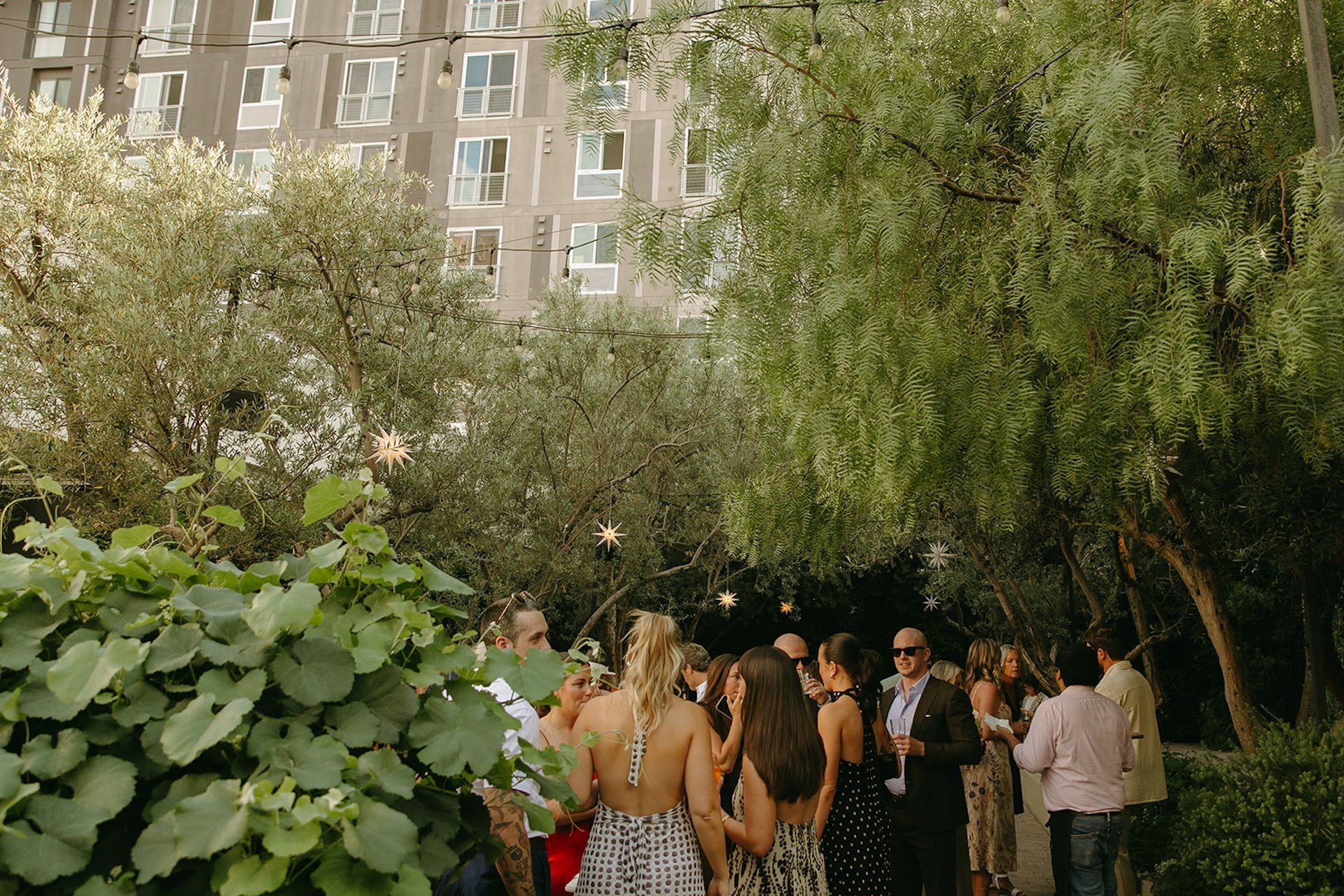 Guests mingling during cocktail hour in a garden courtyard with string lights and greenery, showcasing Intimate Wedding Ideas for relaxed outdoor receptions.