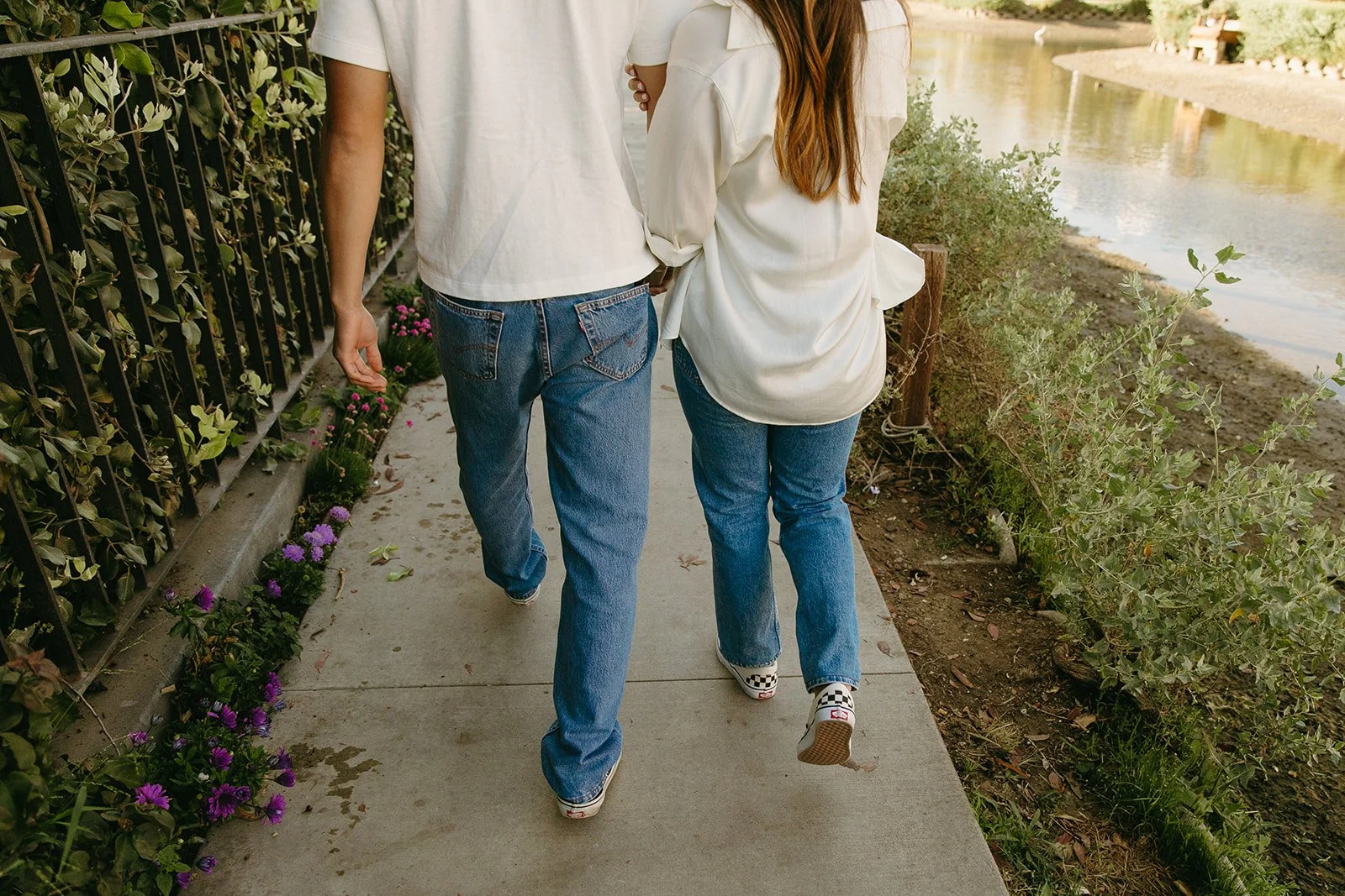 A romantic walking moment along Venice Beach Photoshoot Locations with flowers, greenery, and canal views.