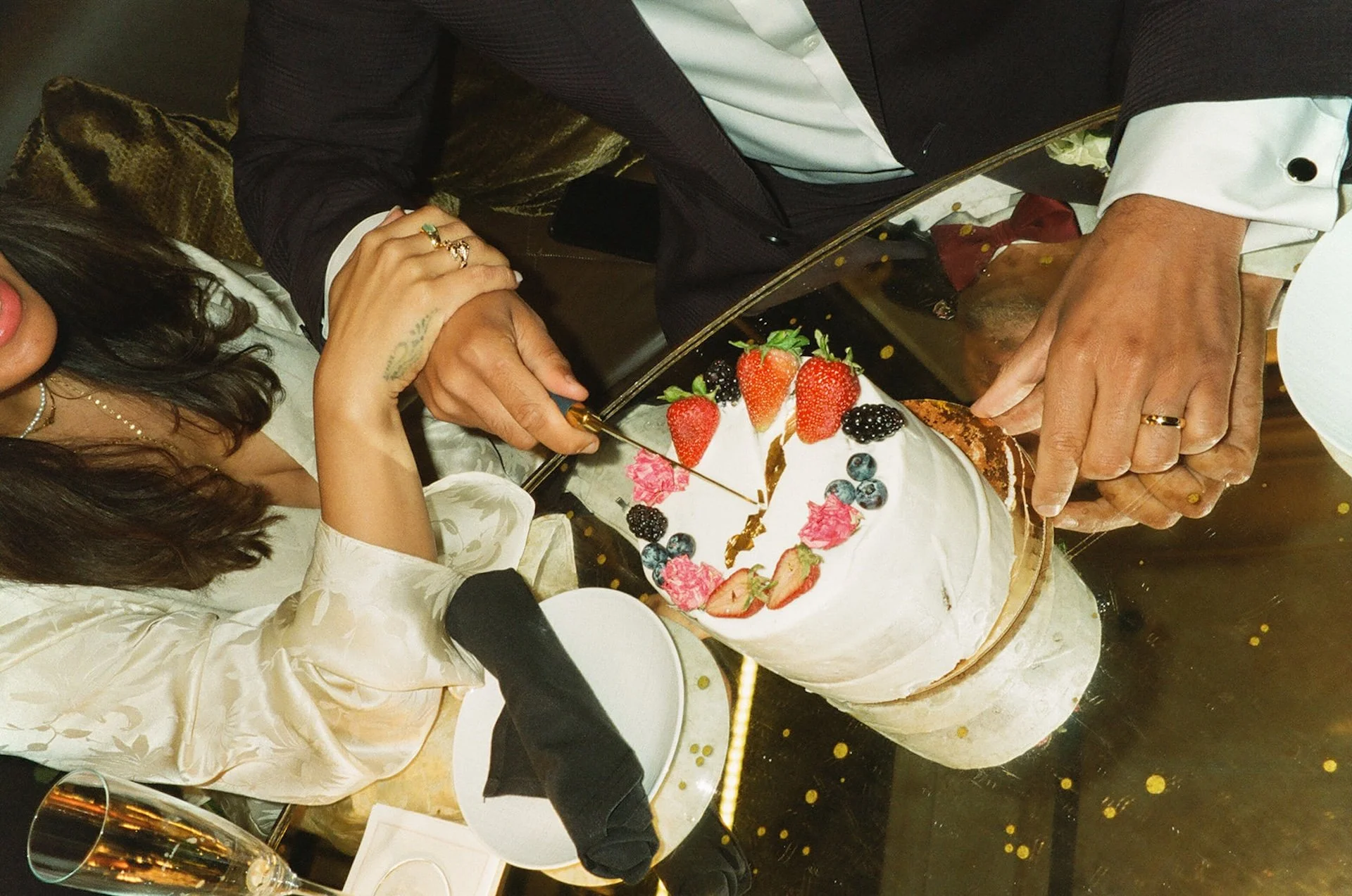 A flash photo of the newlyweds cutting into a small white cake at their dinner after their Beverly Hills Courthouse Elopement