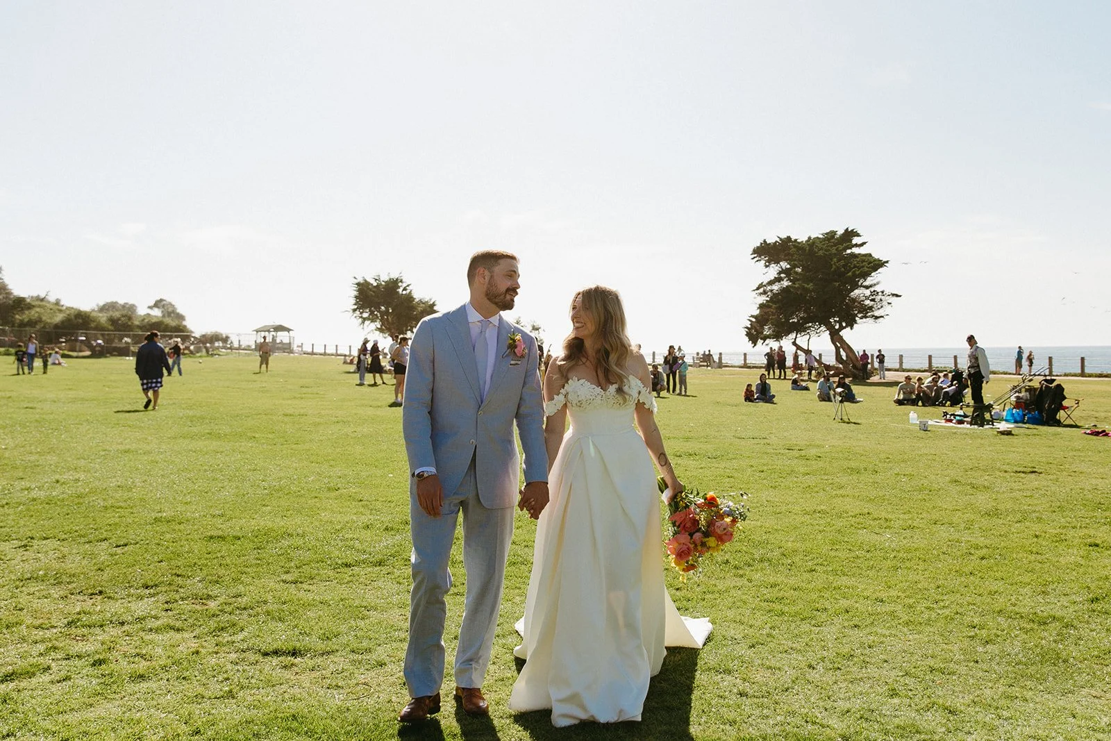 A bride and groom laughing during photos in a park