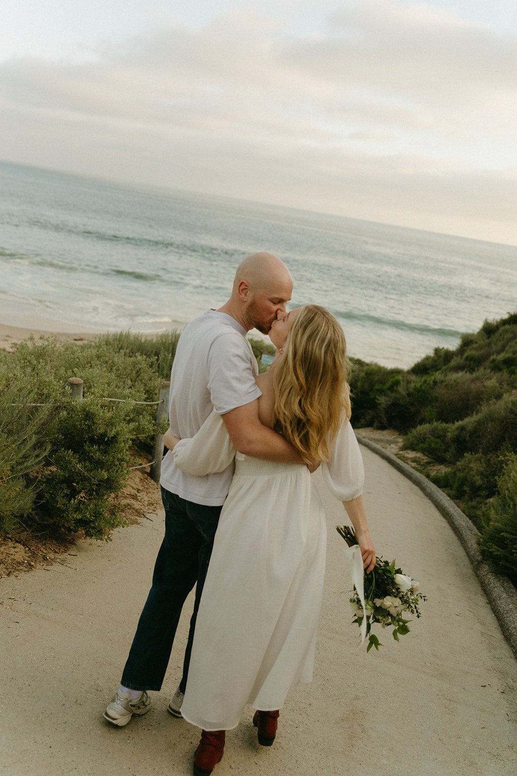  romantic walk along the coastline path, arms wrapped around each other and a bouquet in hand—an ideal setting for relaxed engagement photo tips.