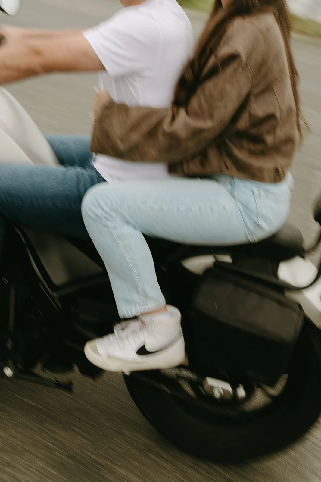 Close-up of a couple on a motorcycle, focusing on their embrace and casual outfits as they ride.