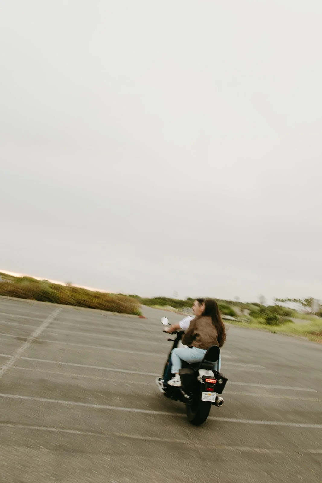 Blurry photo of a couple riding a motorcyle away in a parking lot with the sun setting behind them.